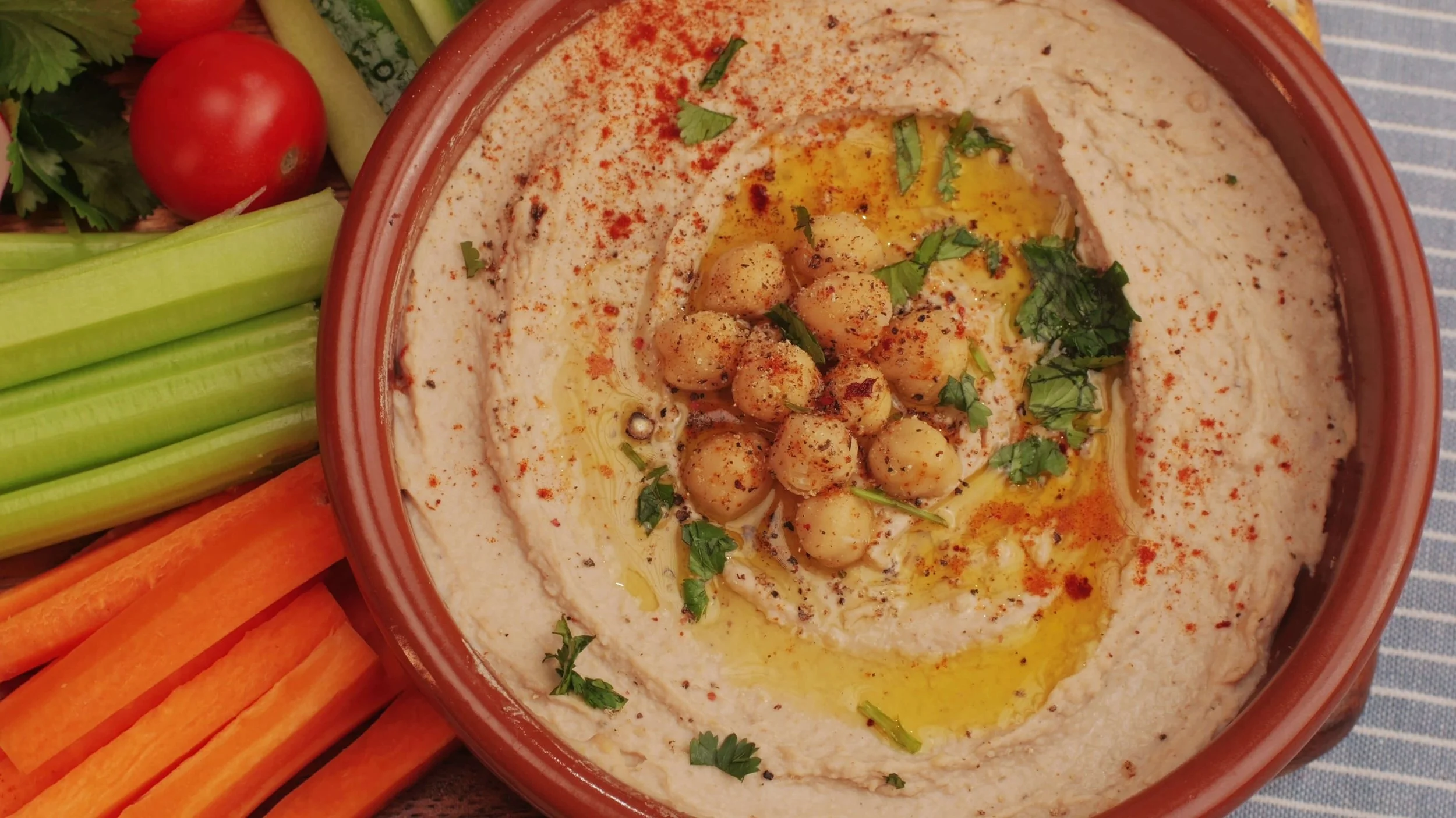 Homemade hummus dip in a bowl surrounded by fresh vegetables