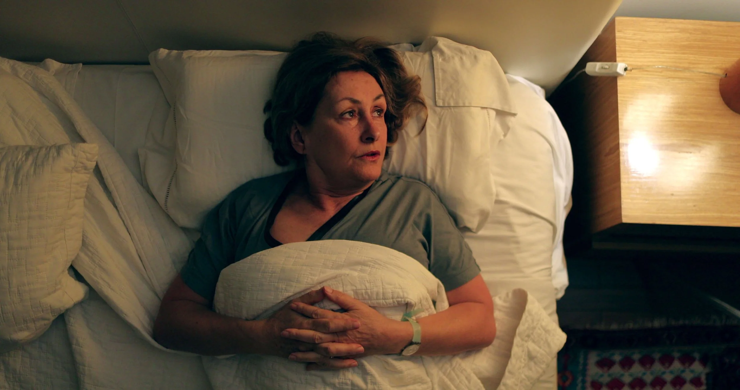 Woman lying awake in bed at night unable to sleep, illustrating the effects of high cortisol on sleep, energy and stress in women.