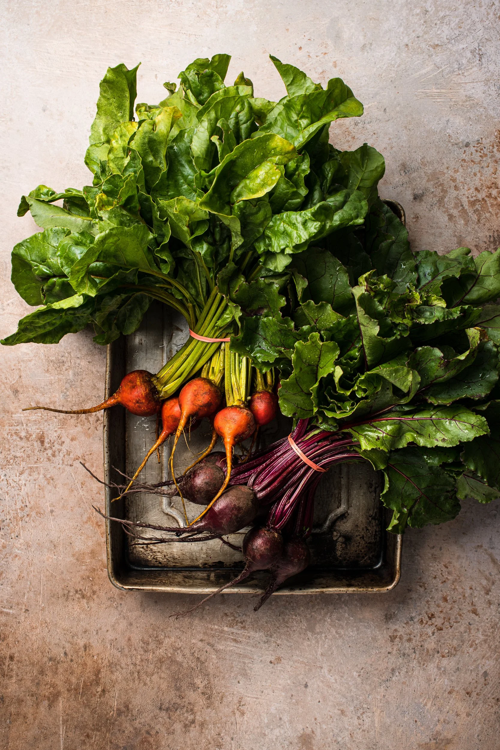 A bunch of golden beets and a bunch of red beets on a tray