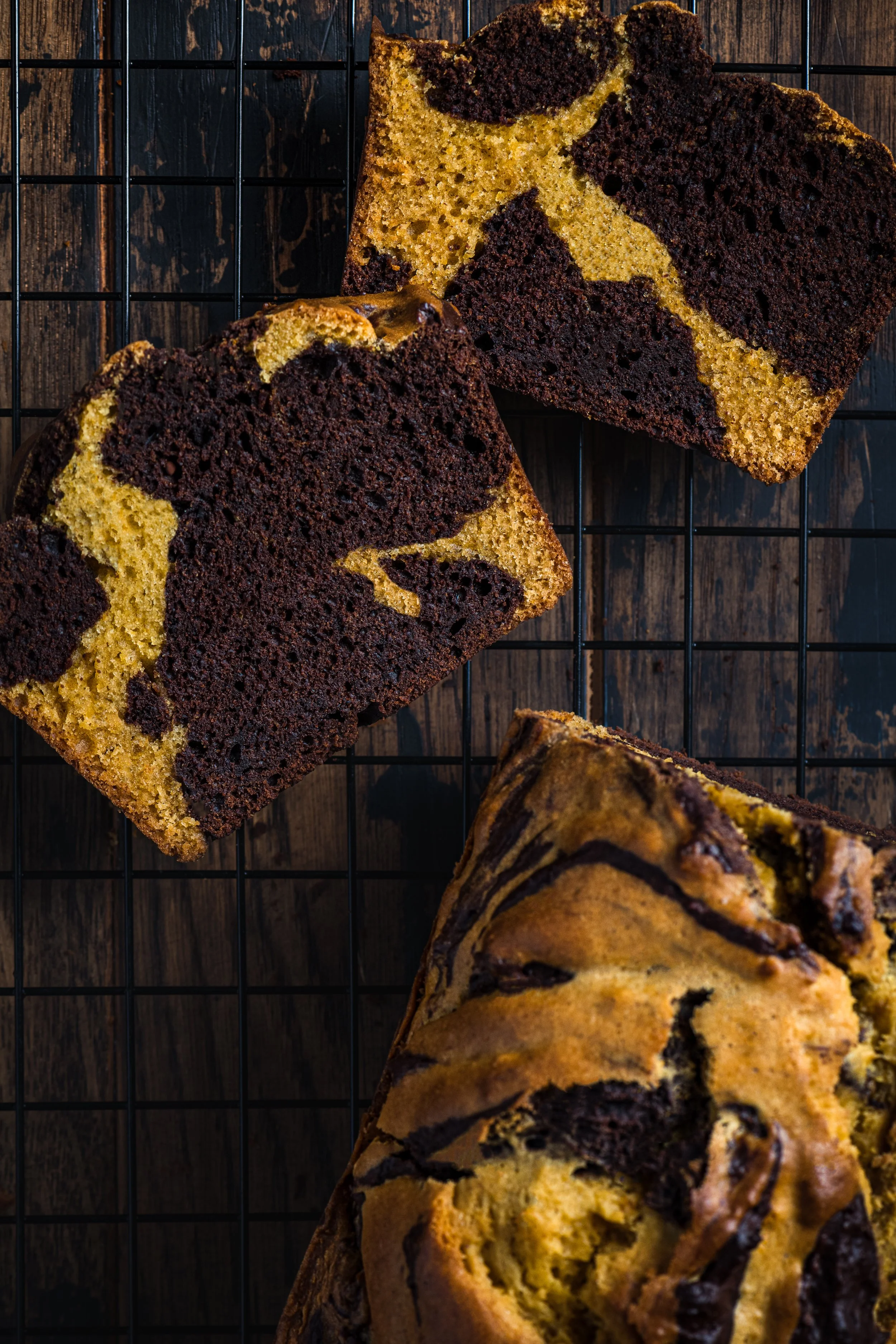Two slices of marbled loaf cake on a cooling rack