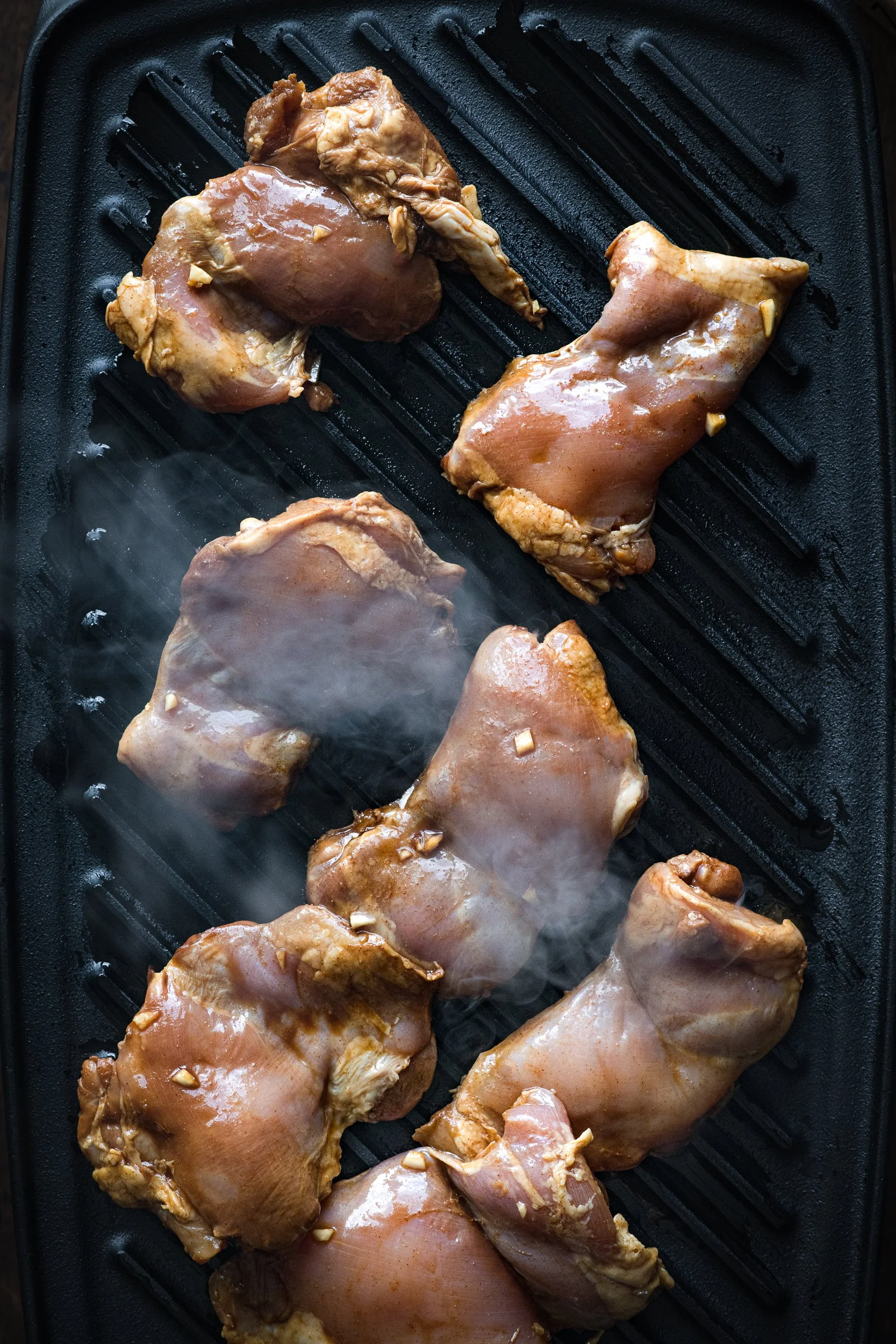 Chicken thighs being grilled on a cast iron grill pan