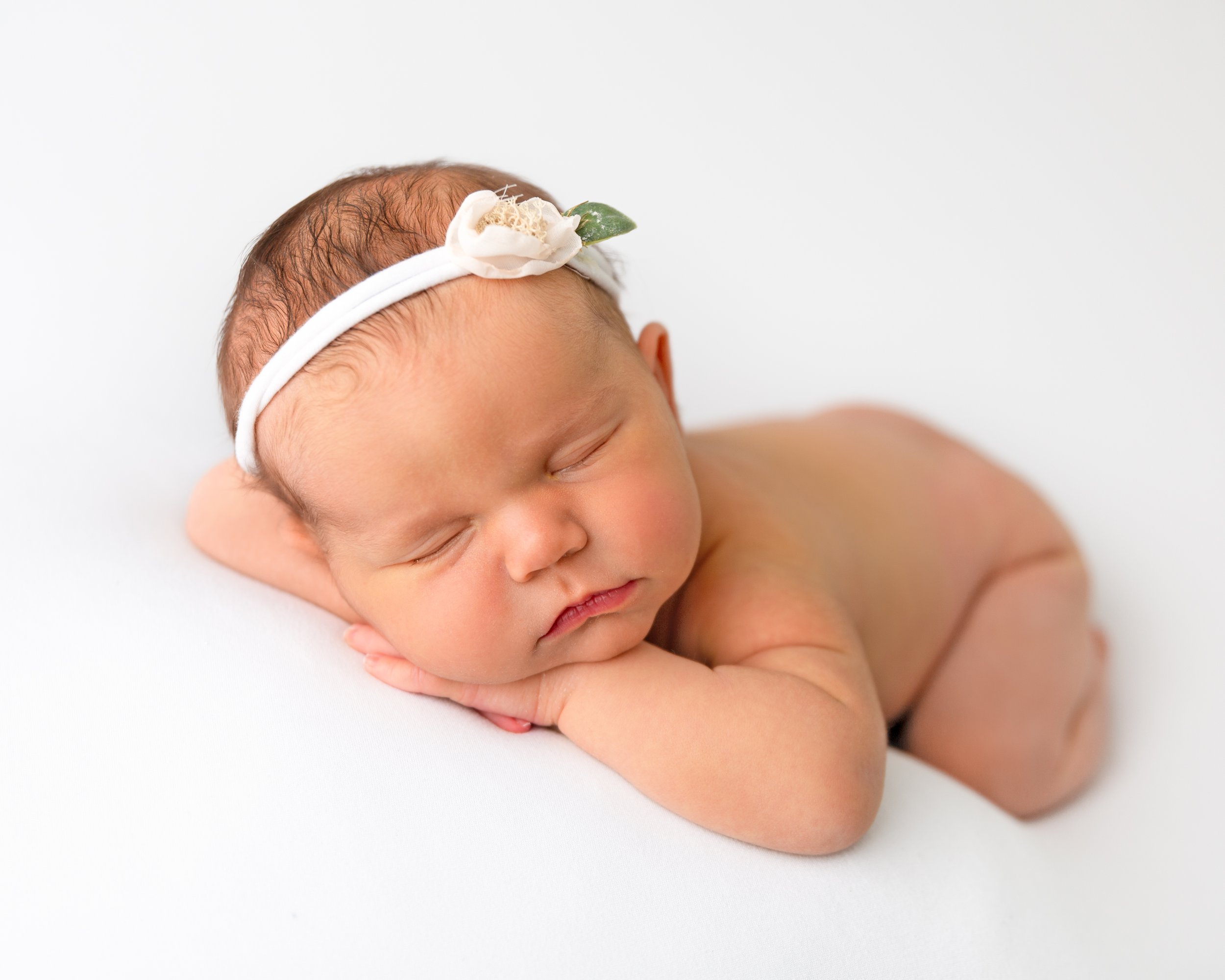 Newborn baby with her chin on her hands