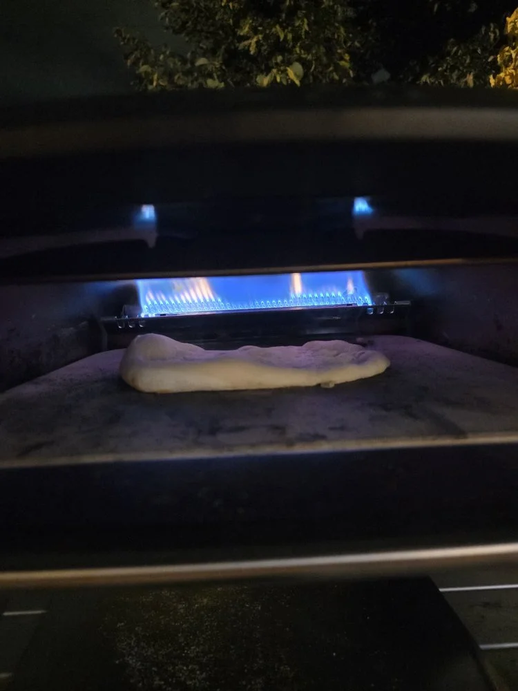 garlic naan dough cooking in an ooni pizza oven