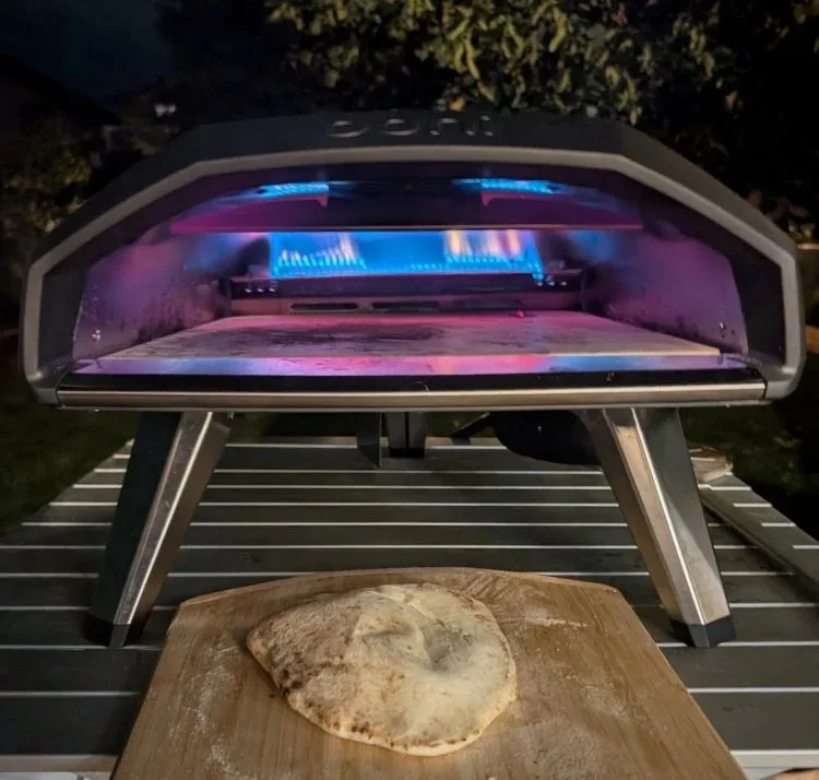 ooni pizza oven with cooked garlic naan on the peel
