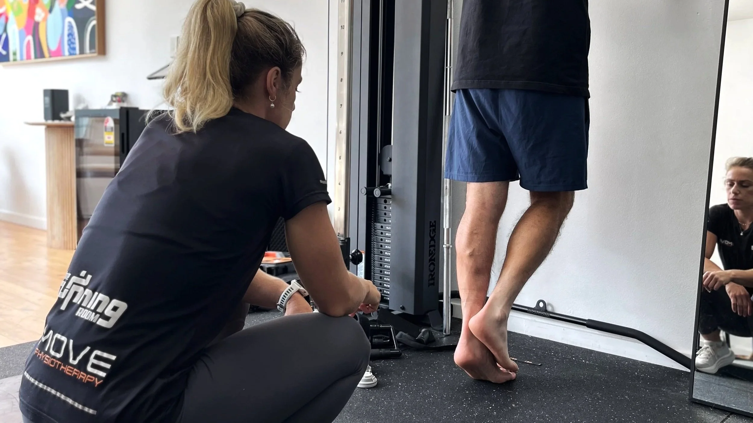 Running Room physiotherapist guiding a patient through calf raise rehabilitation for Achilles tendinopathy