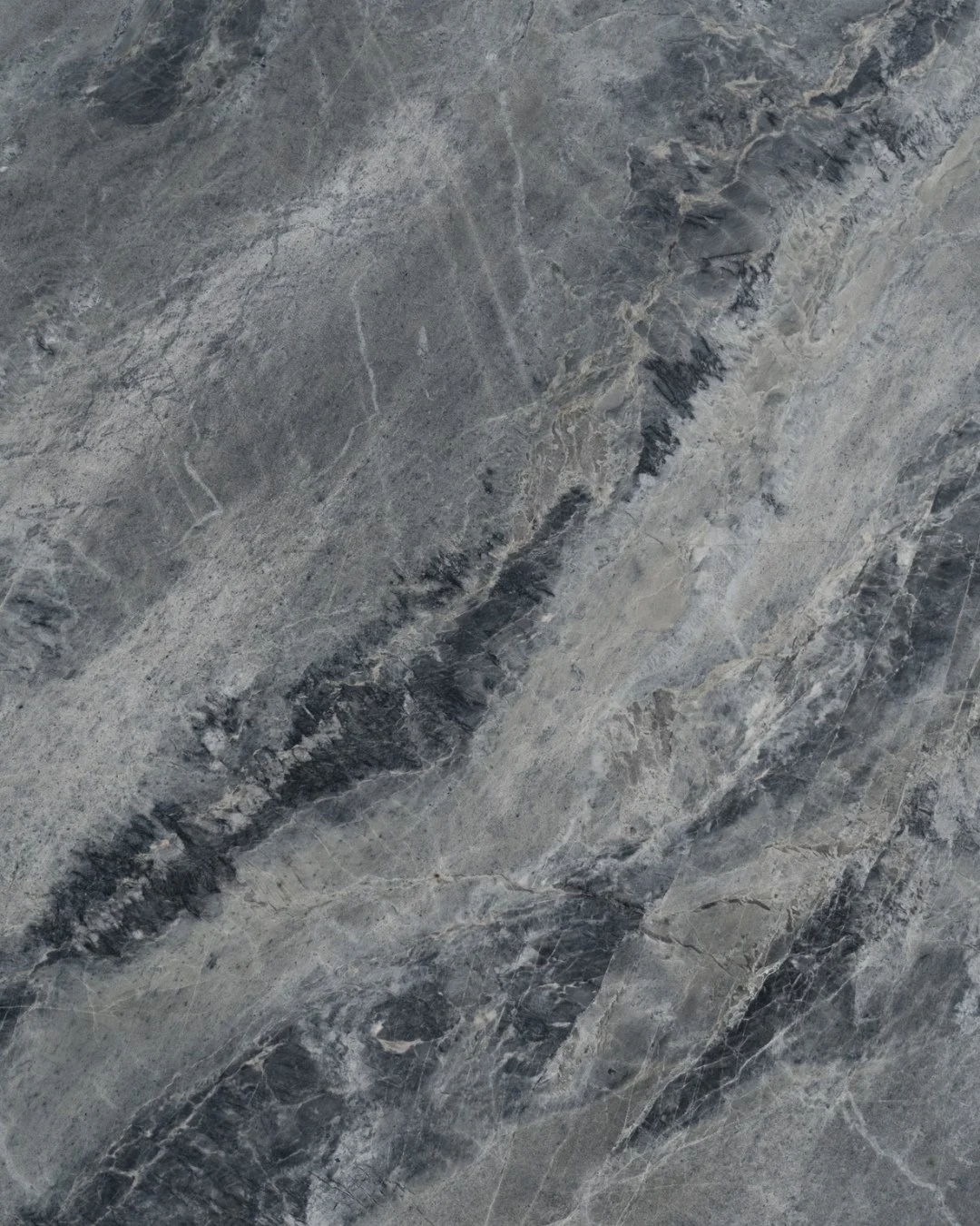 En blågrå quartzite med markante årer og tydelig personlighed. 
De lyse og mørke strøg skaber en naturlig dynamik, der giver pladen dybde og bevægelse – som et landskab i konstant forandring.
Q1910 er