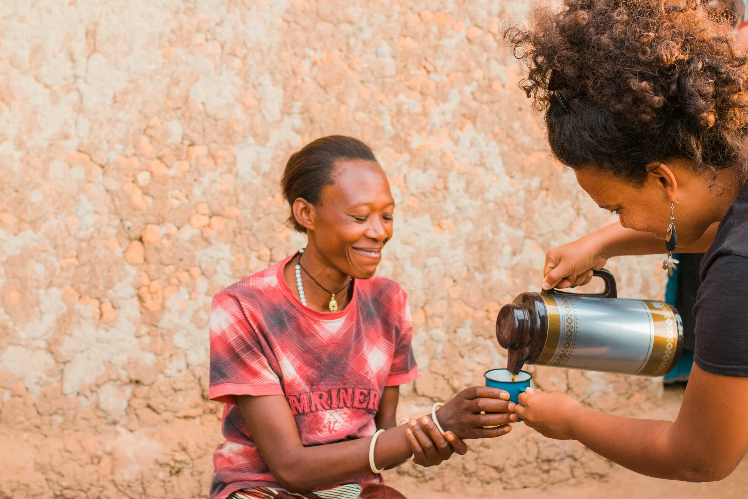 Dorothy of Gaharo Hill in Burundi being served her very first cup of coffee by Lauren, General Manager of Long Miles Coffee Project. Dorothy delivers coffee cherries to Long Miles' Bukeye washing station.