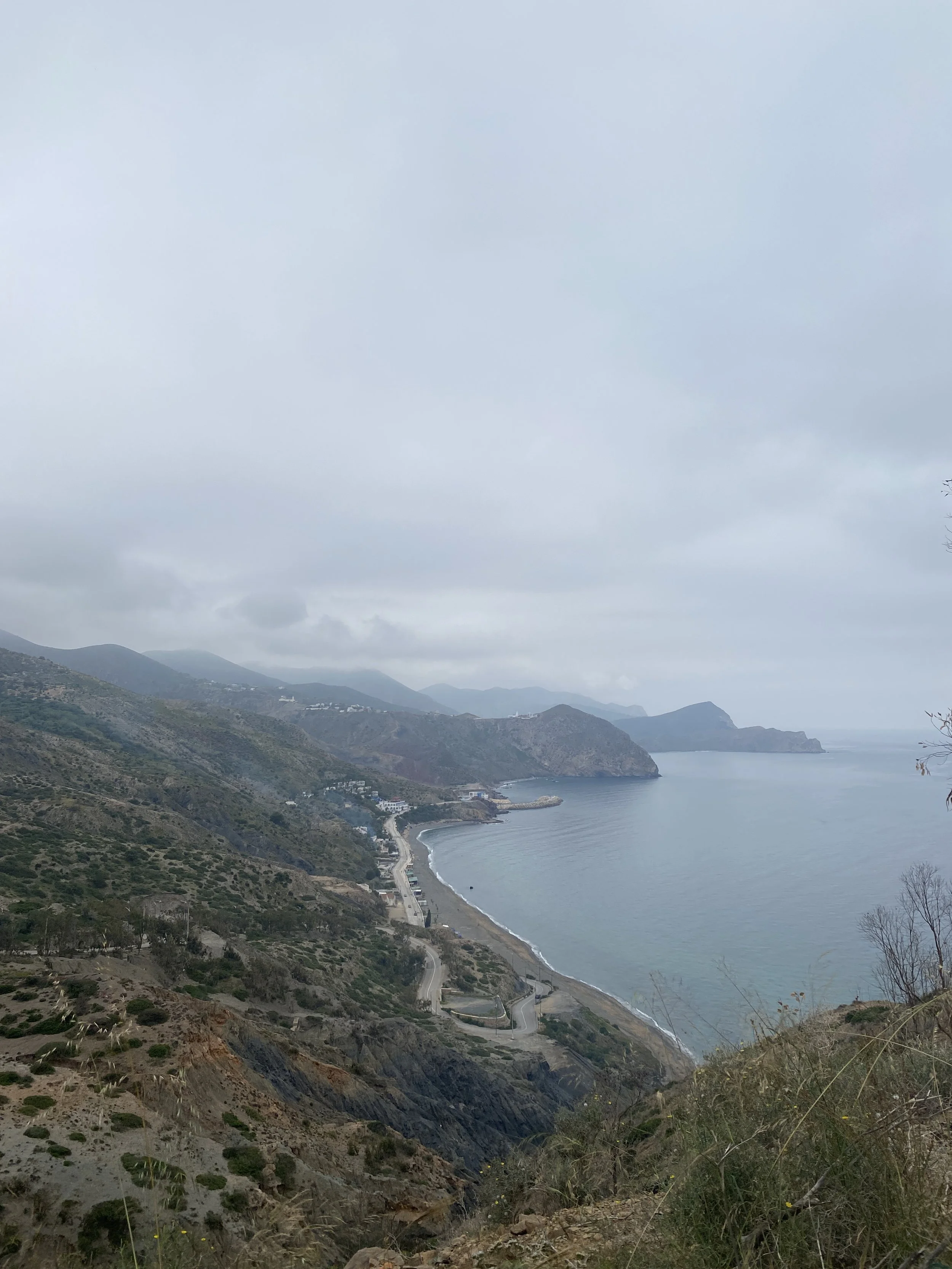Shot of a small beach town with mountains towering over the beach from a viewpoint