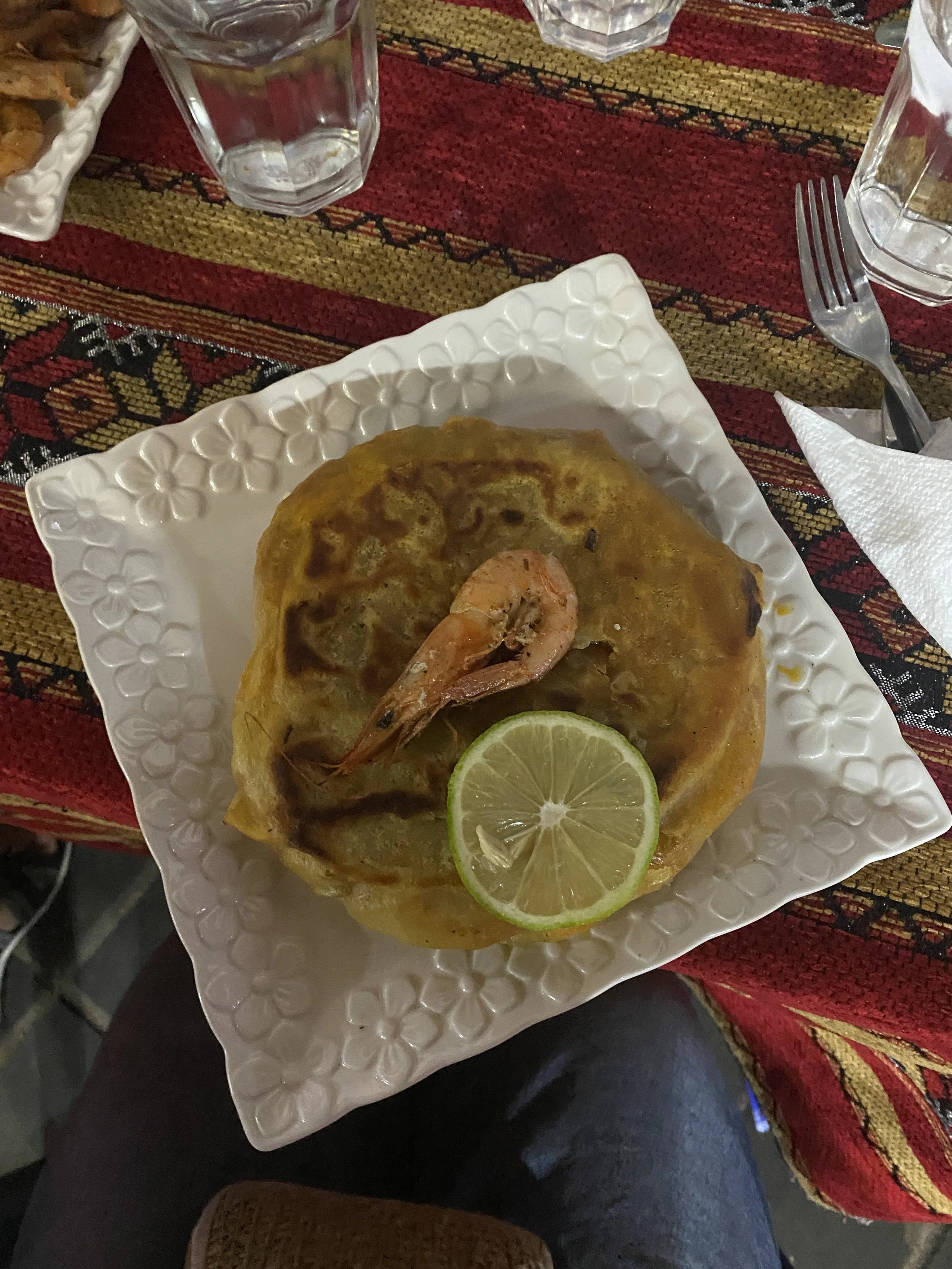 A plate of a fish dish with a shrimp on top at a restaurant.