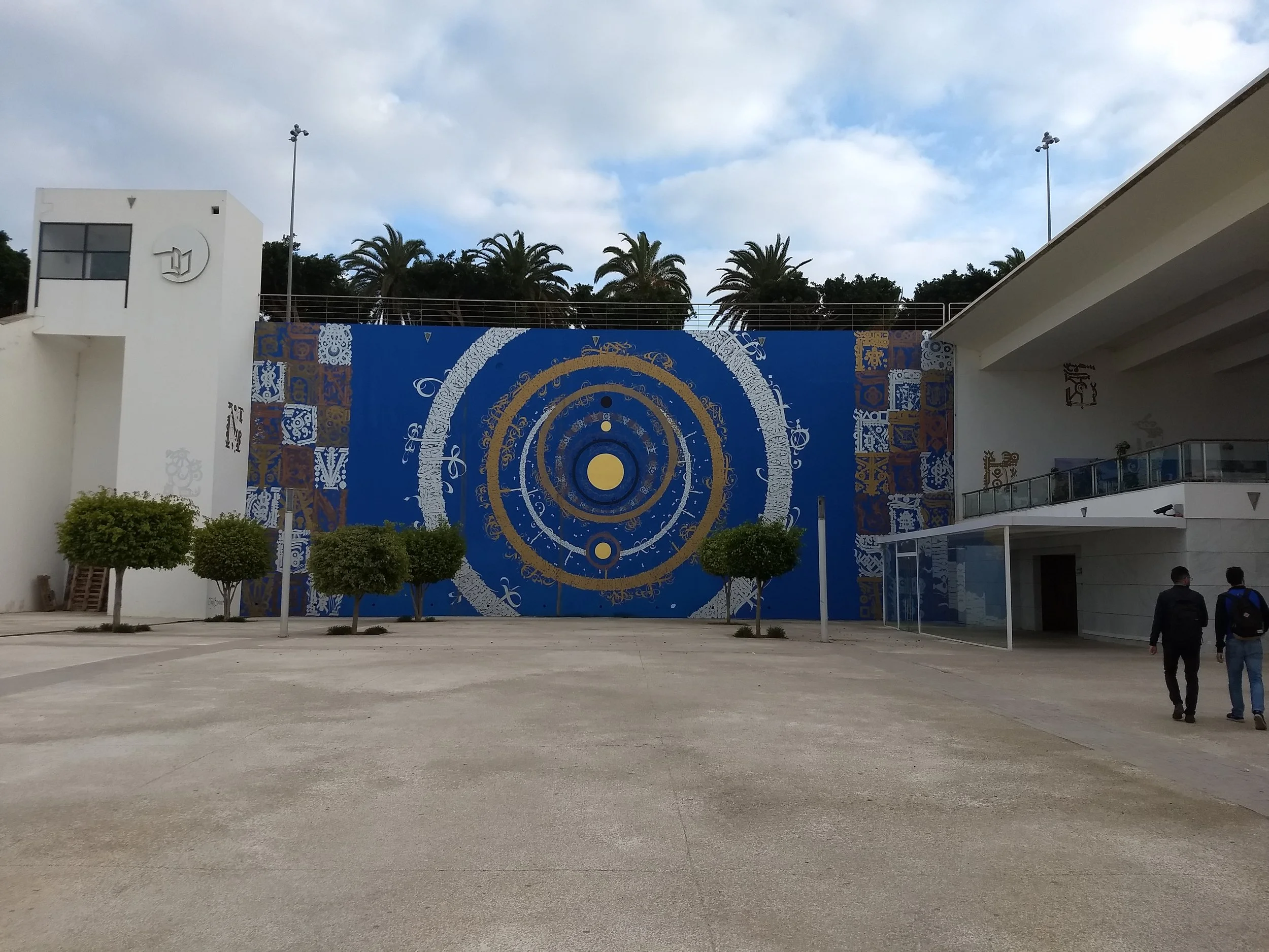 The library is set back from the road, on the other side of a large courtyard filled with sculptures and murals. Photo Credit: Liora Silkes, 2018.