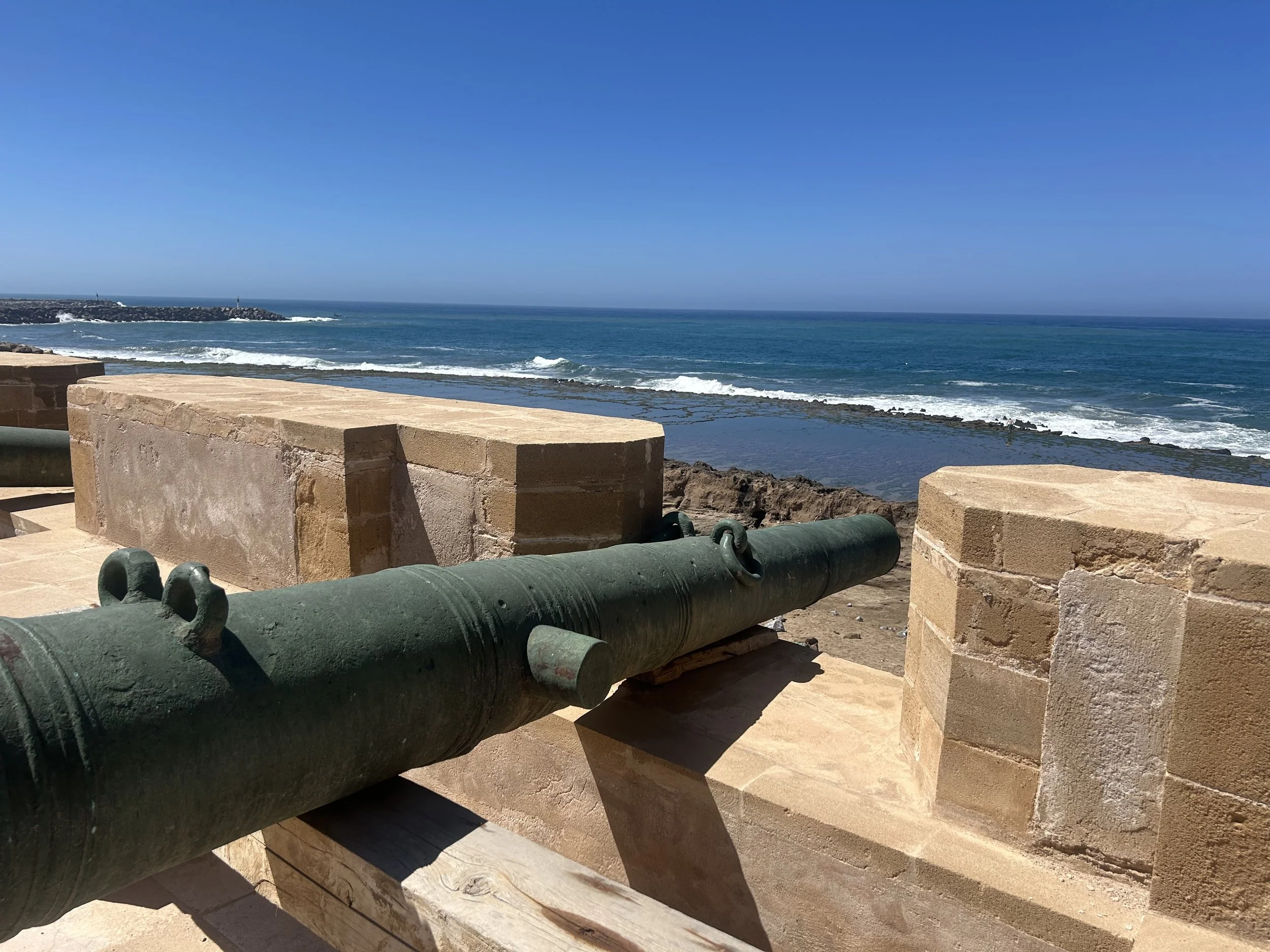 A canon poised on an old fortress wall that formerly defended the city. The sea is in the background