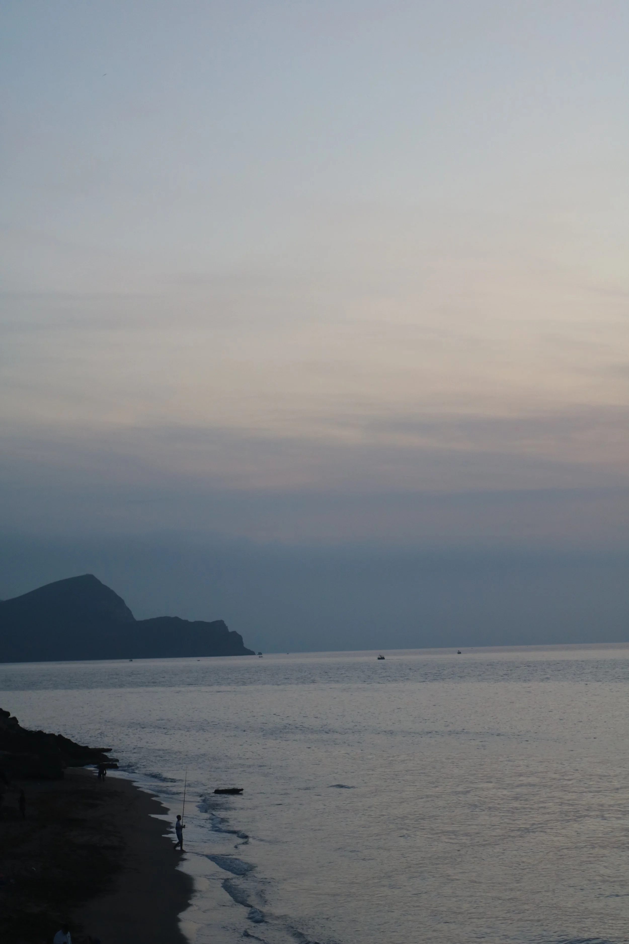 The sun sets over the water and the cliffs near the shore