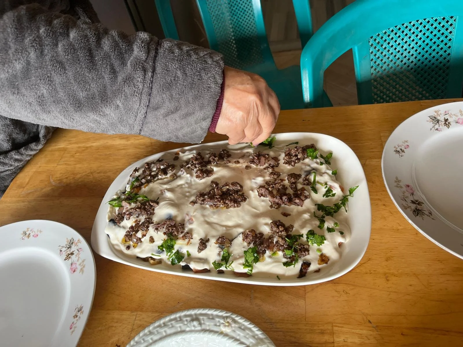 Someone sprinkles parsley on top of the dish.
