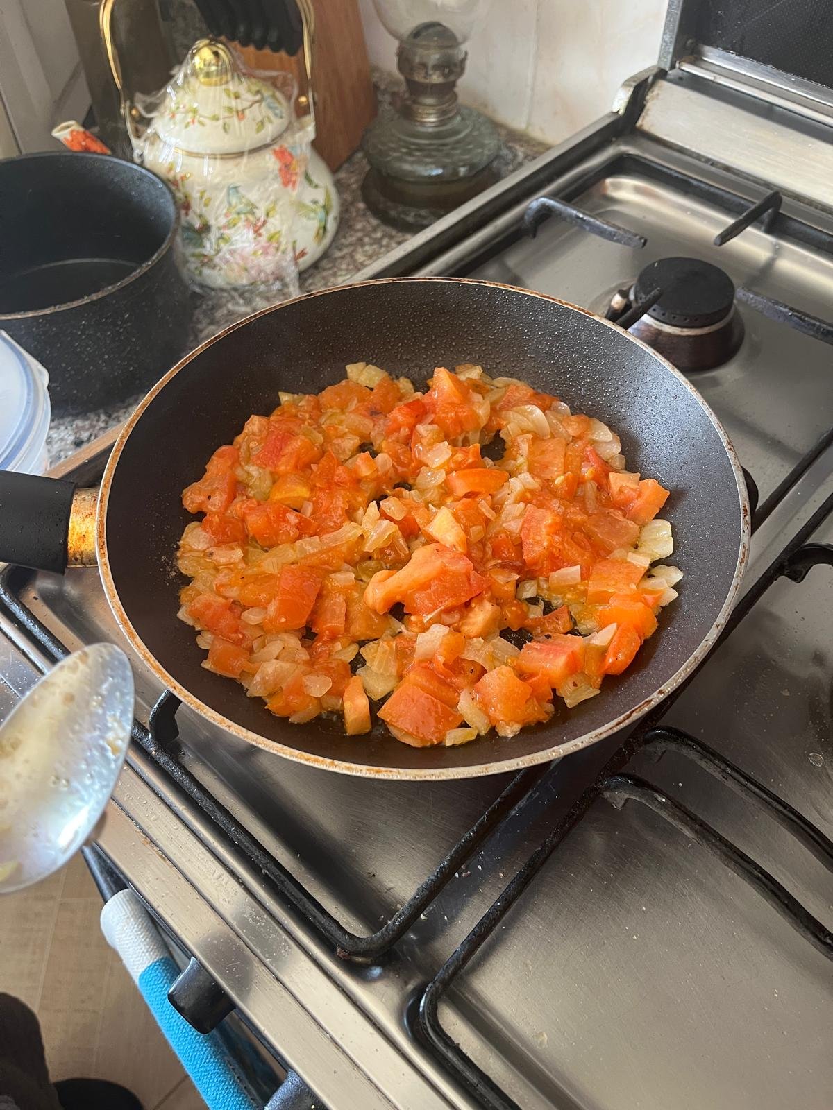 Chopped tomatoes cook in a pan on the stove