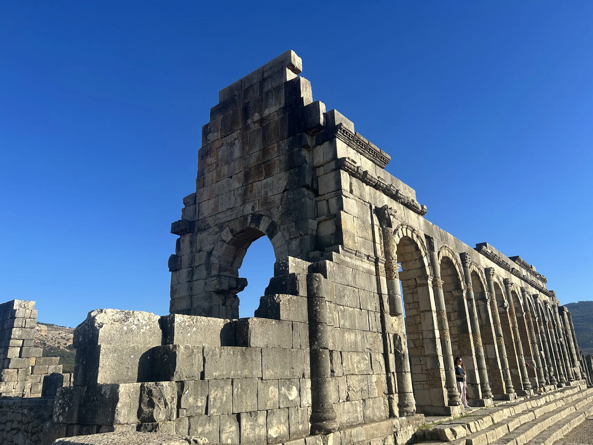 Ruins of a basilica under a blue sky. Many archways remain intact