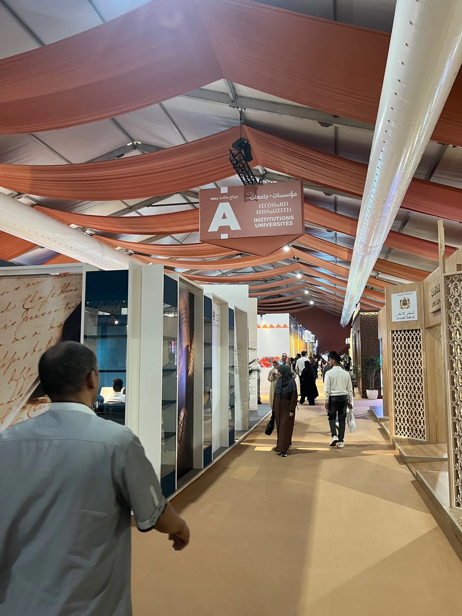A hallway in a convention center space with people looking in at different stalls