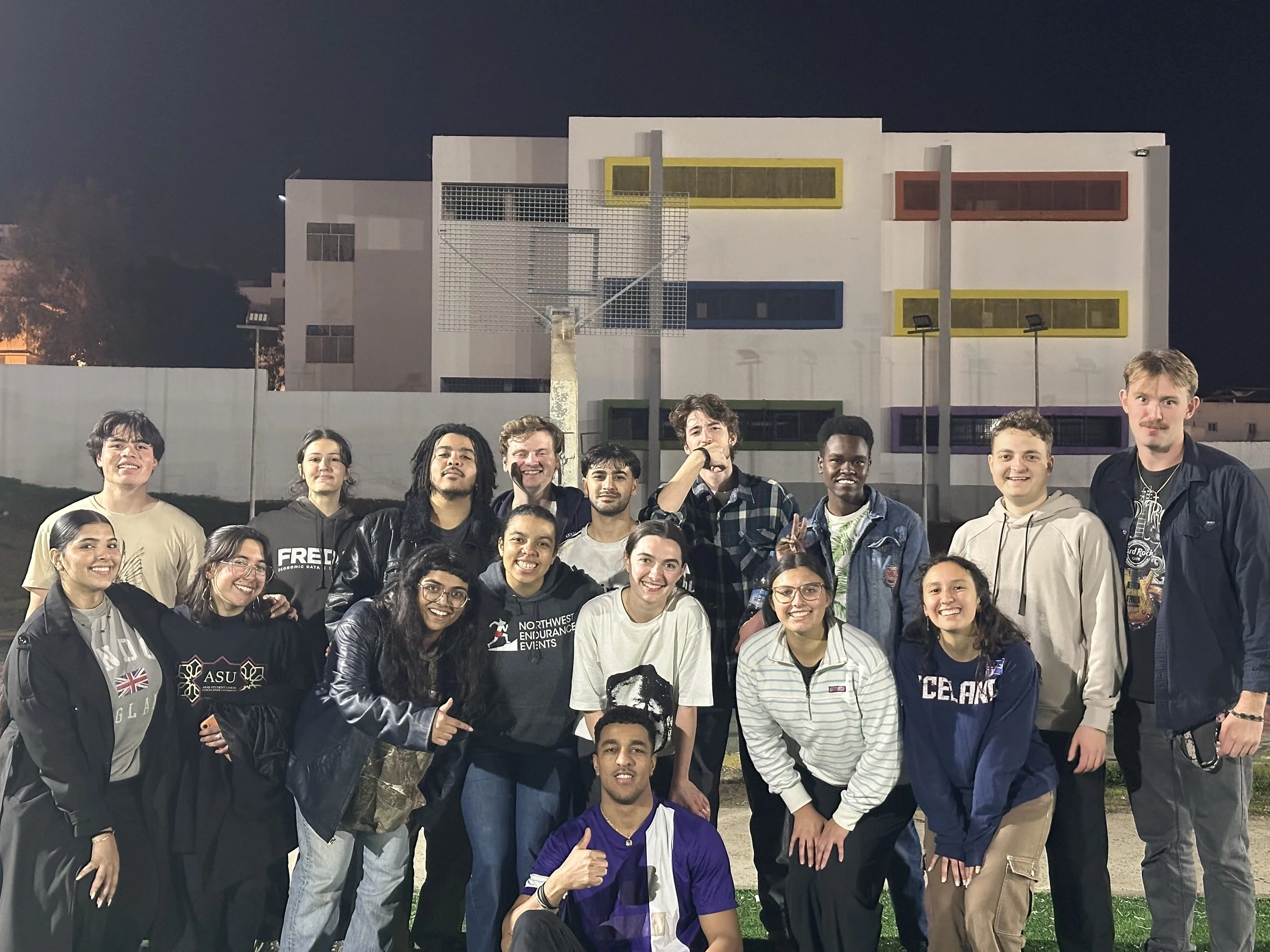 A large group of young people smile for a group photo on an athletic field.