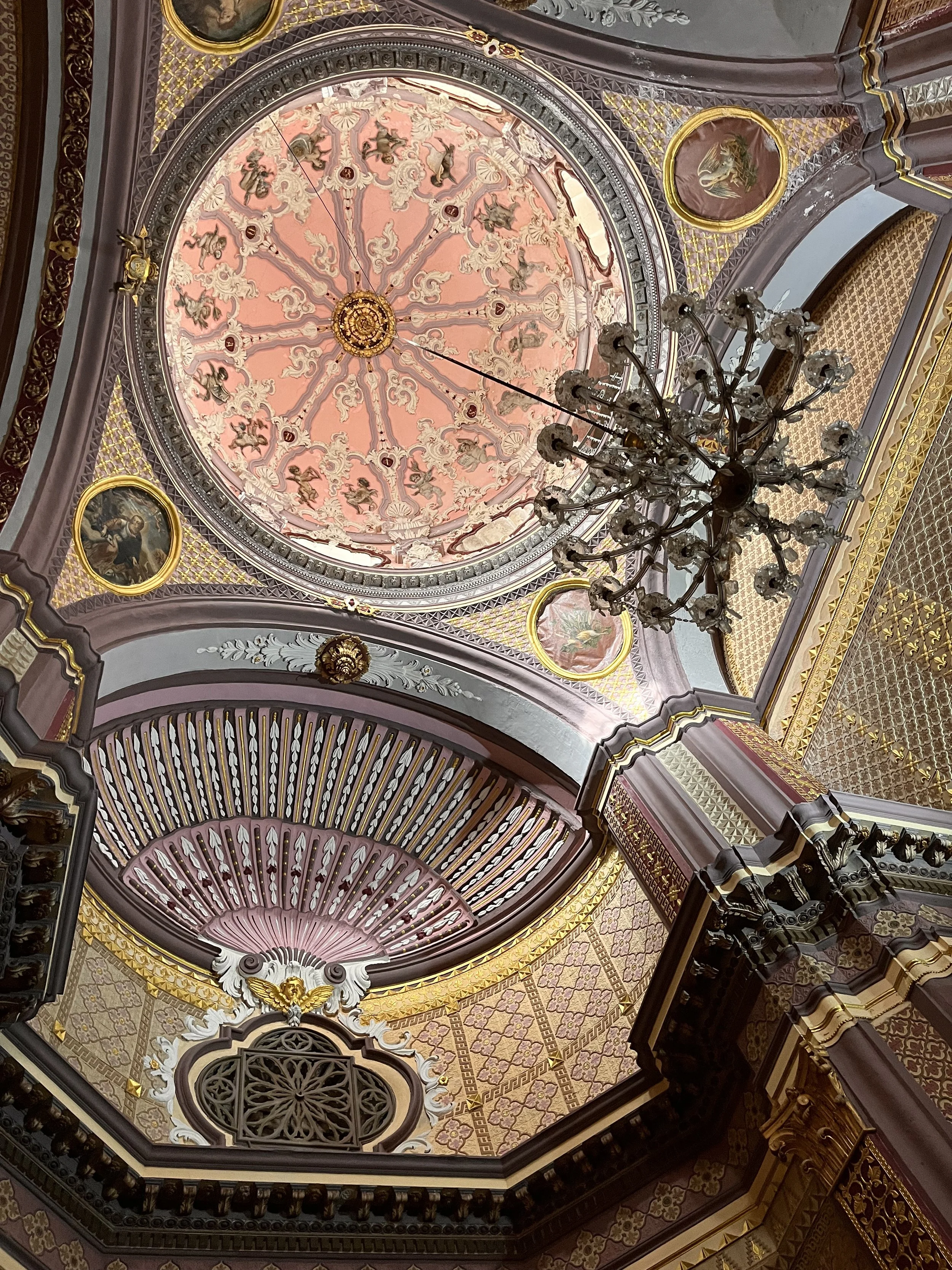 Looking up into a pink dome painted with biblical motifs.