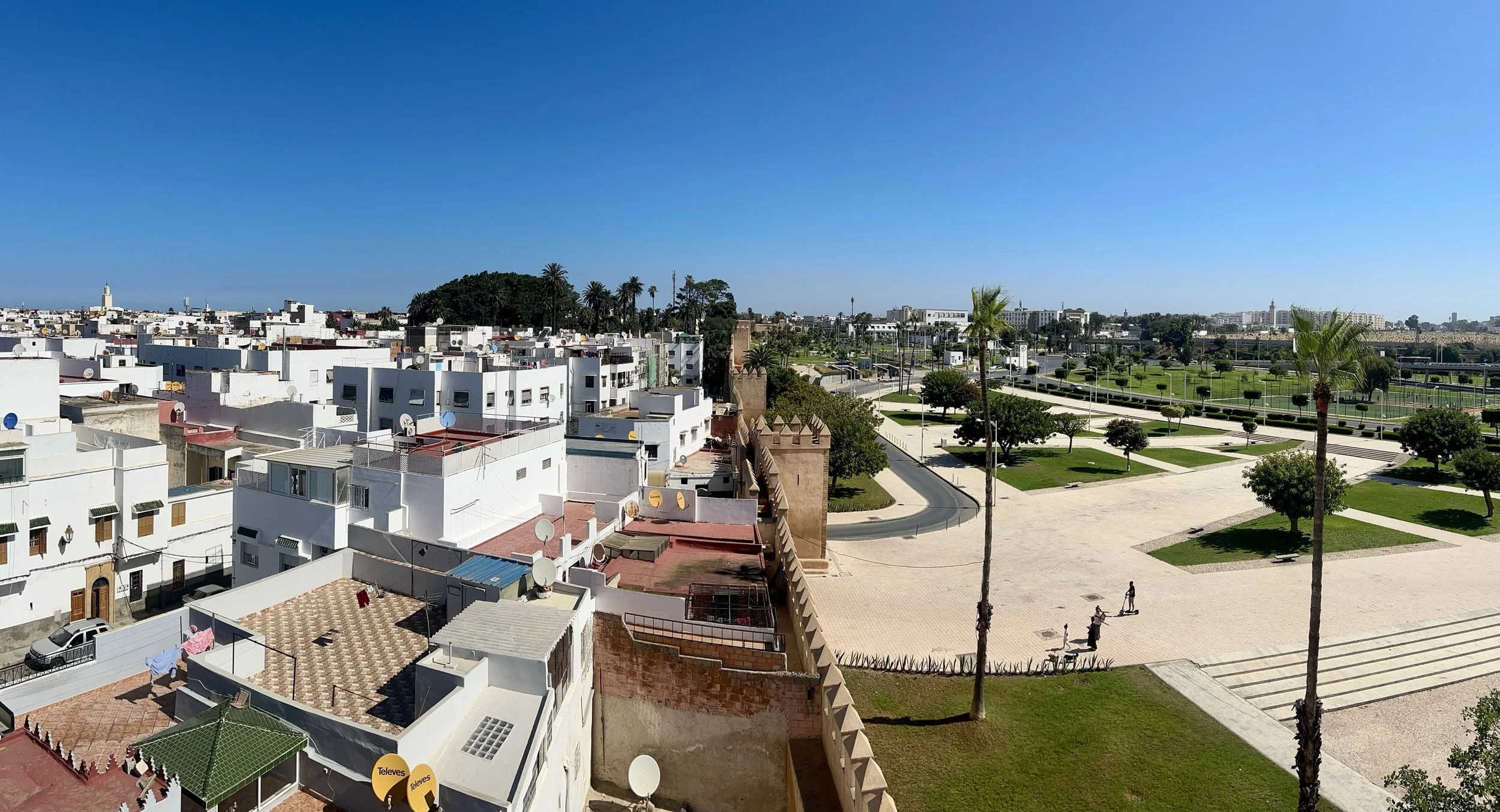 A wide angle shot of the city of Sale from the walls showing a green space with plazas on the right of the wall and white houses tightly together on the left.