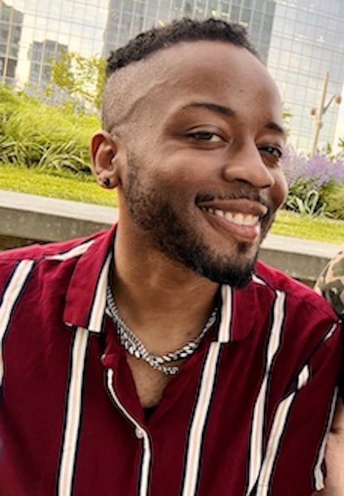 A young man takes a selfie. He is smiling, and wears a striped red and white shirt.