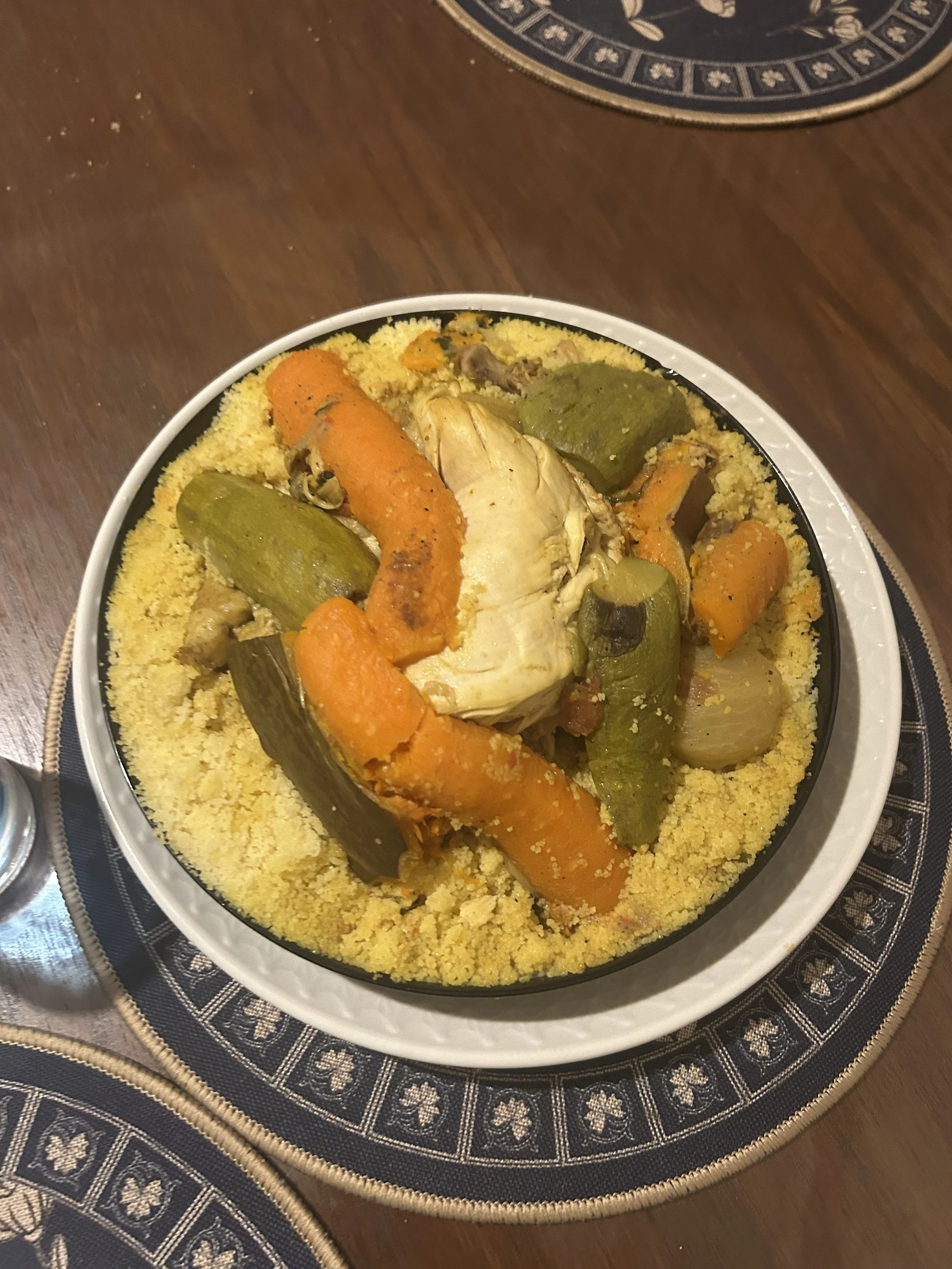 A bowl of couscous with carrots, chicken, and zucchini