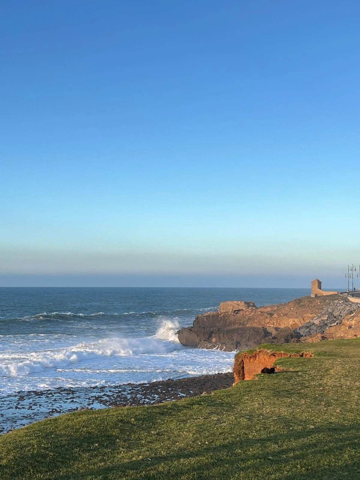 The coastline of Morocco as the waves come up to the cliffs on a sunny day with a blue sky
