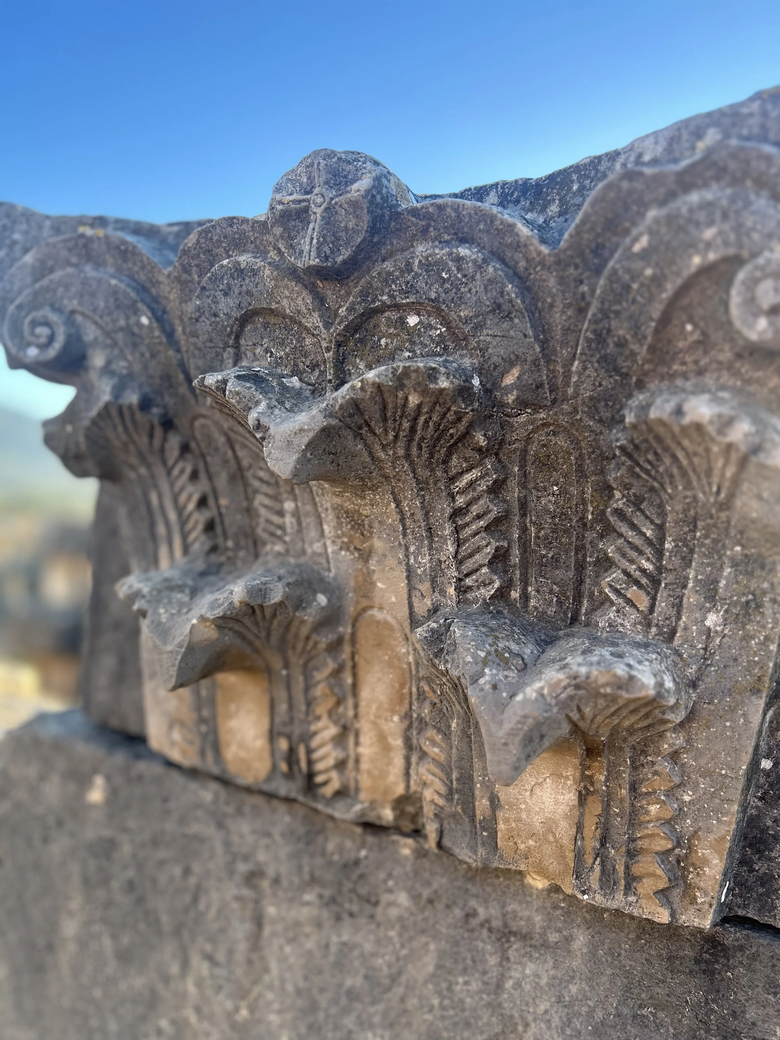 A close up image of the top of a column showing a cobra like pattern with many cobra heads jutting off of the column