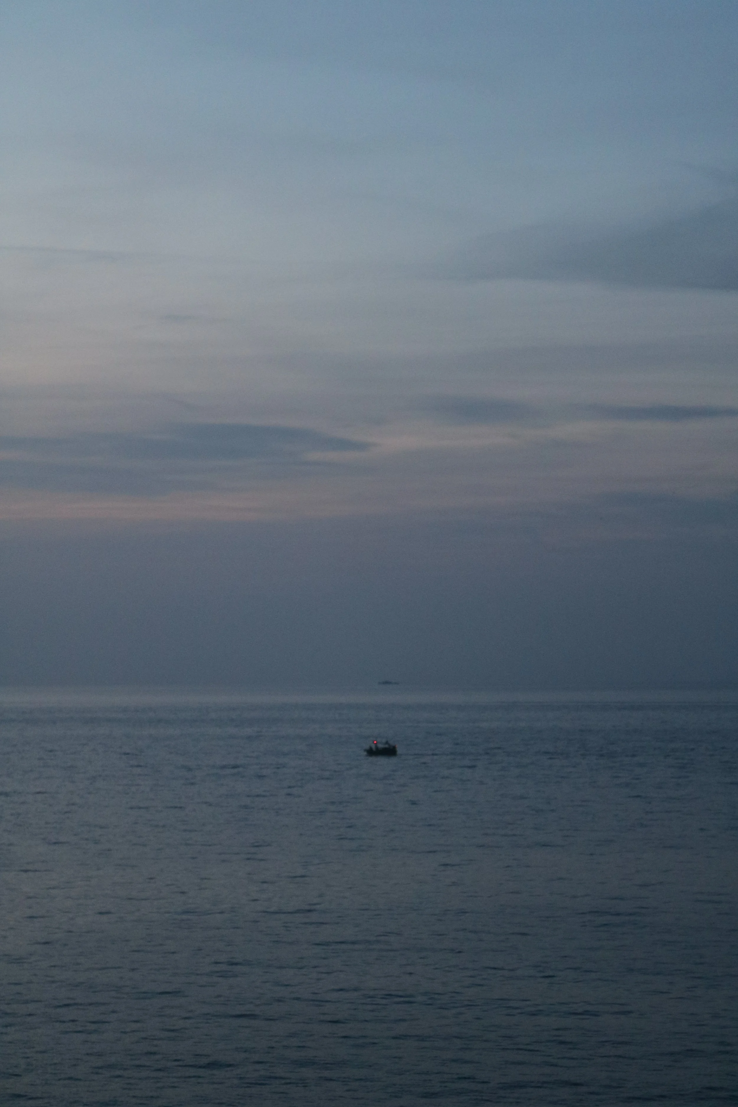 A boat sits on the open sea under gray cloudy skies