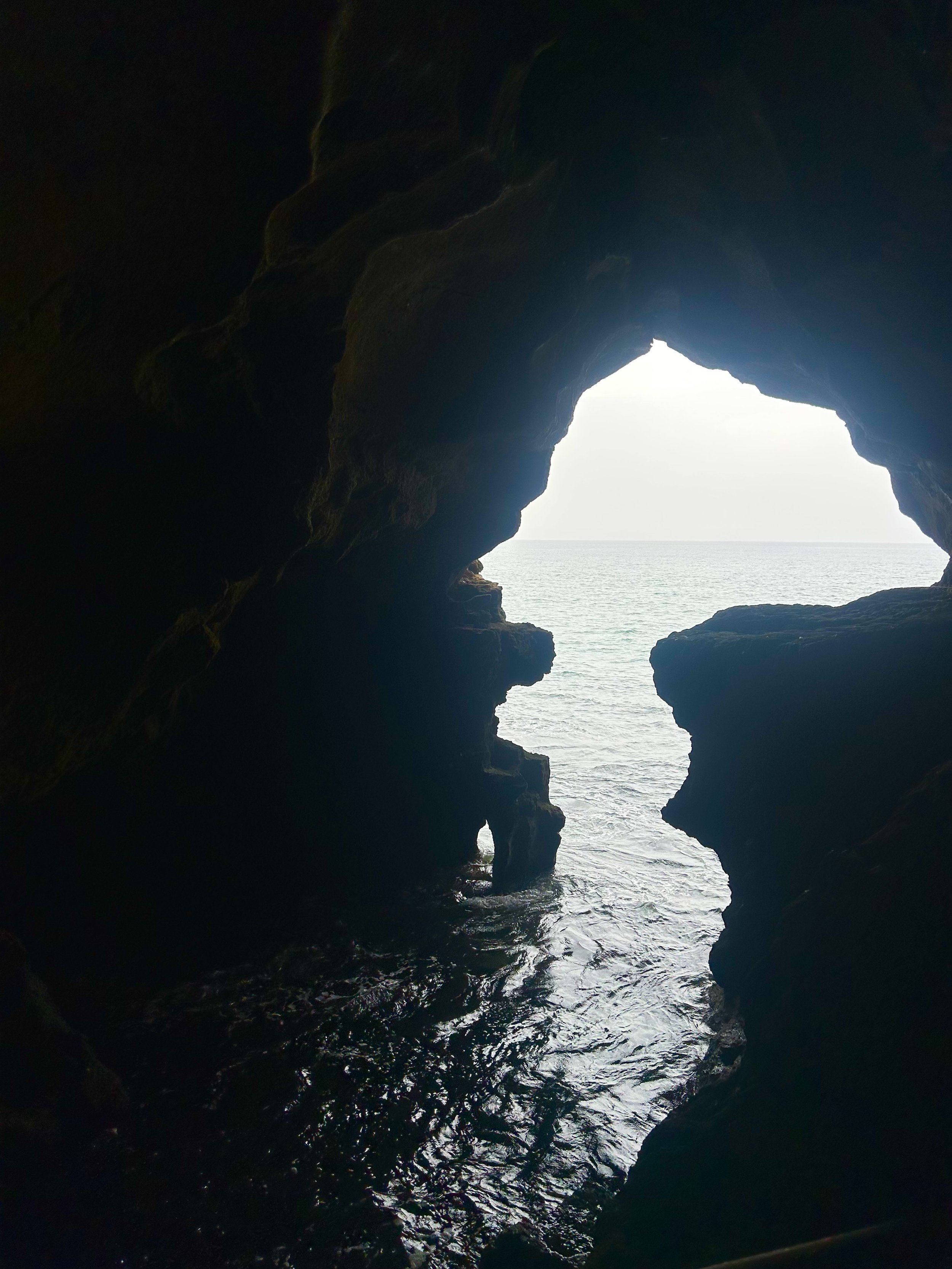 From inside a cave, the opening appears as a bright spot, letting in the light from out at sea. The opening resembles the shape of Africa