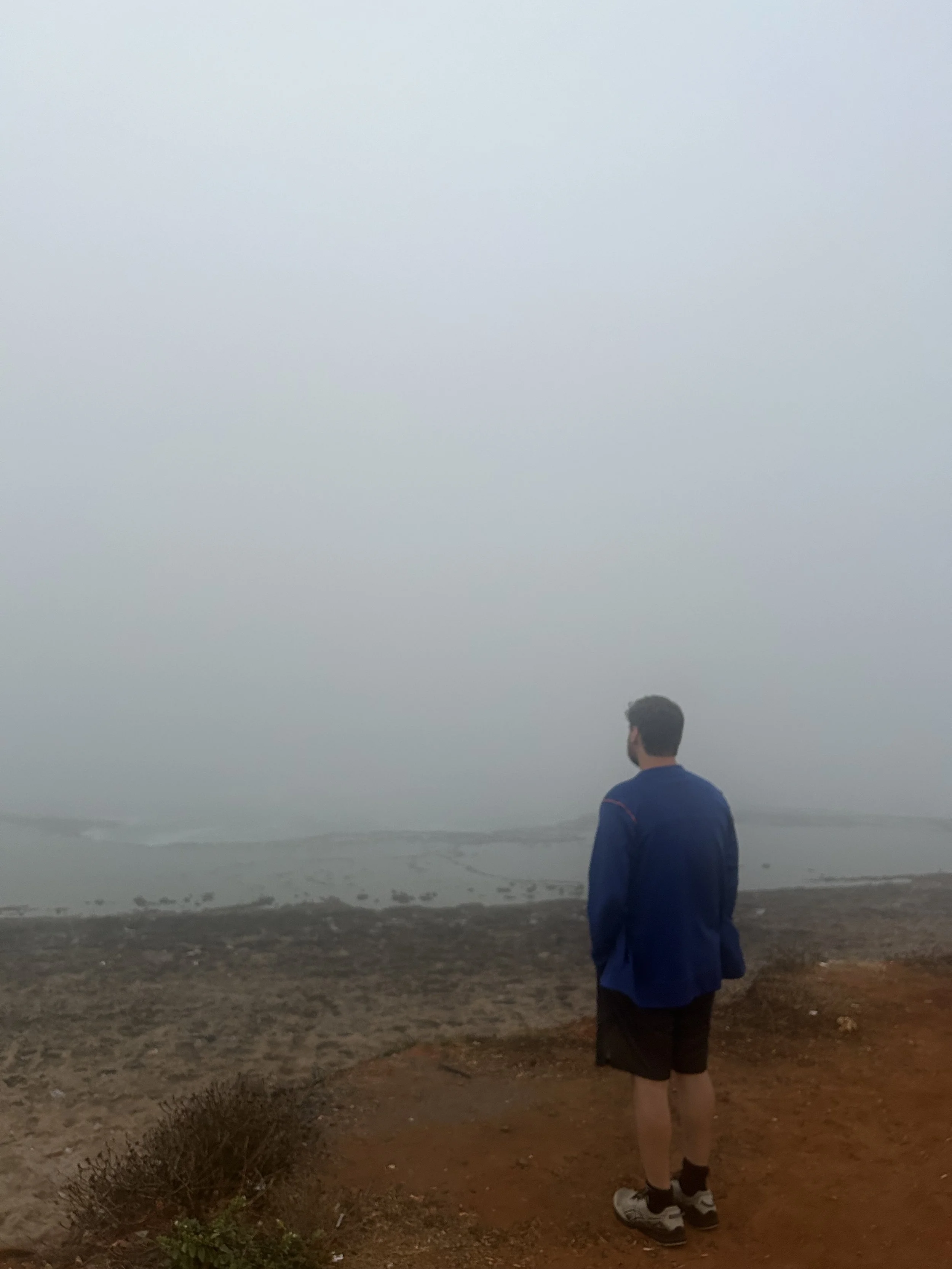 A man stands in the mist on the beach and looks out at the sea. The difference between the sea and the sky