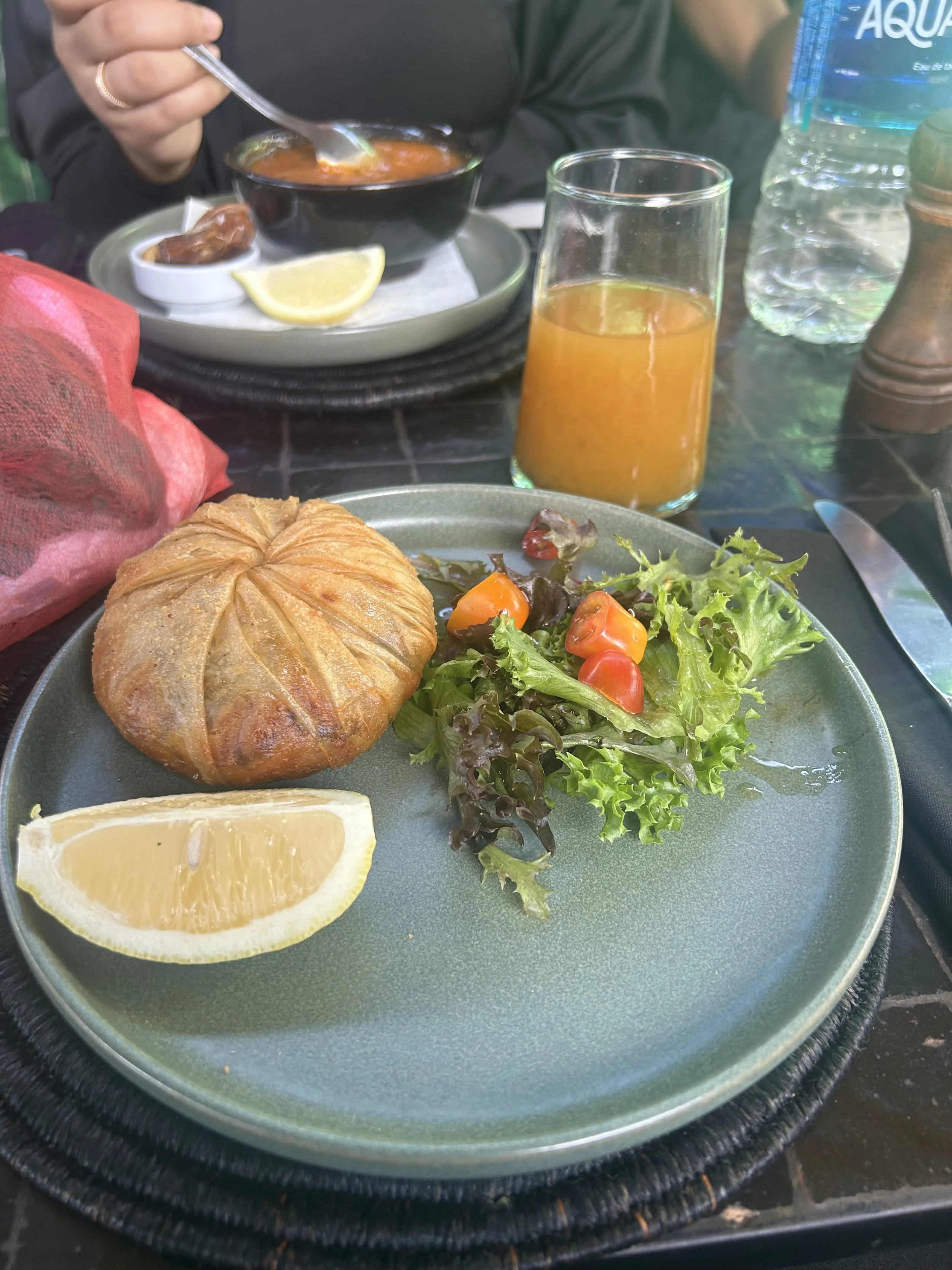 A salad sits next to a puff pastry food and a lemon.