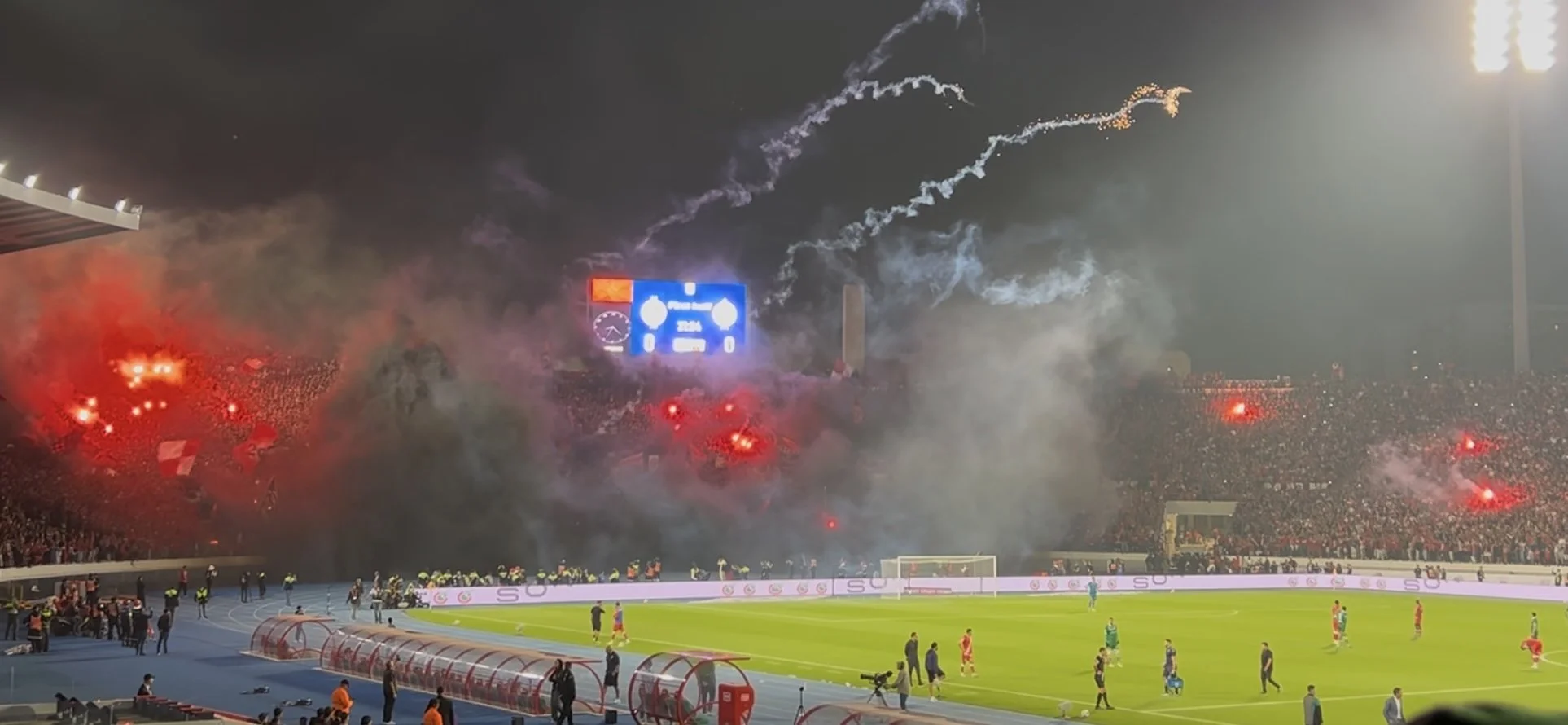 Flares and smoke come from one supporter section at a football game