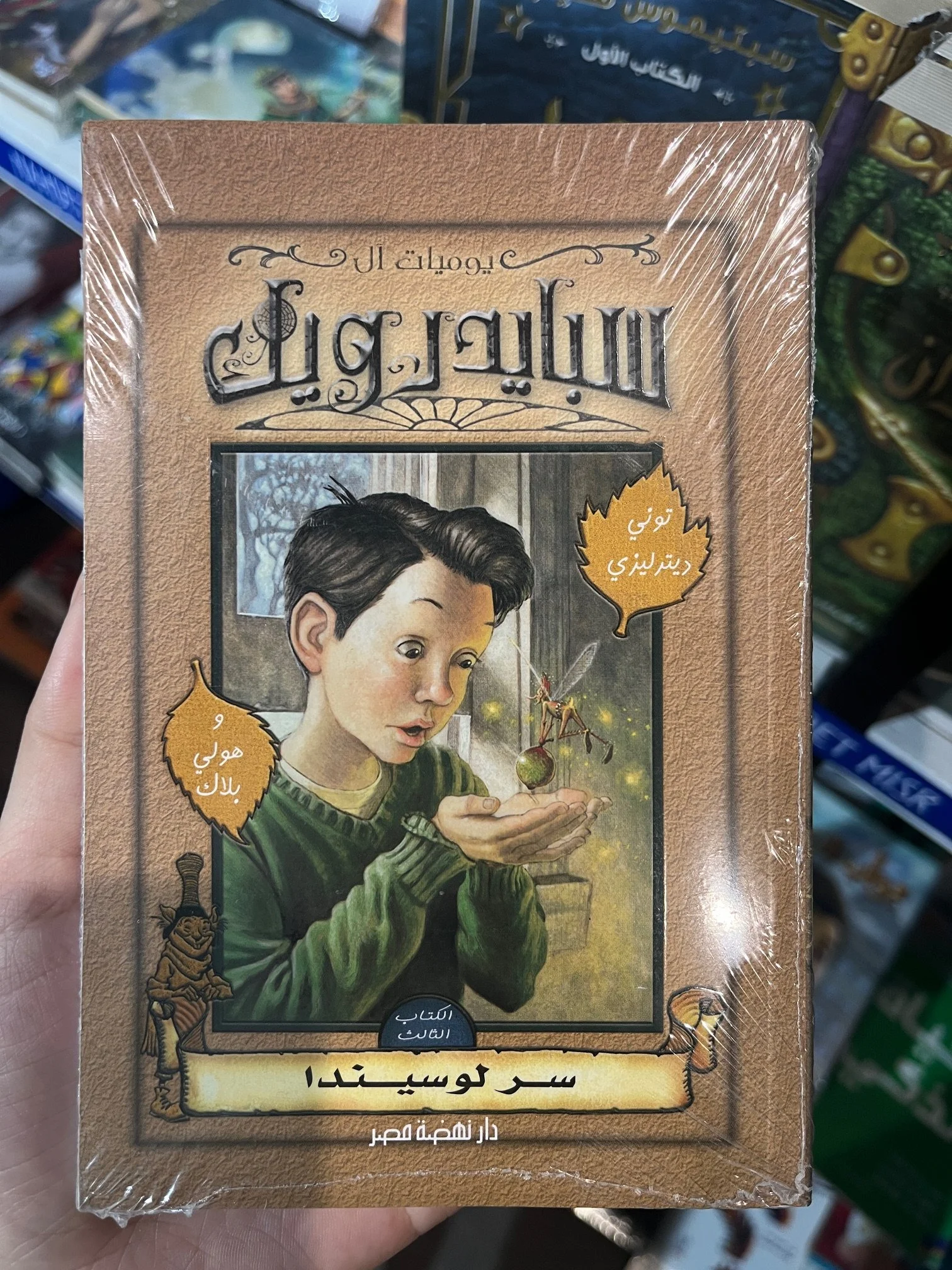 A copy of Spiderwick in Arabic held up in a protective plastic cover