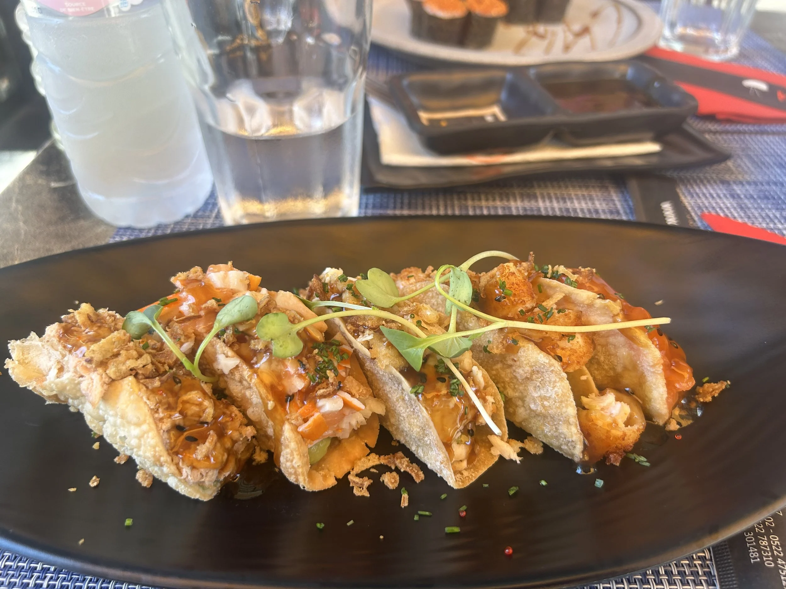 Five fish tacos sit beautifully presented on a black plate.