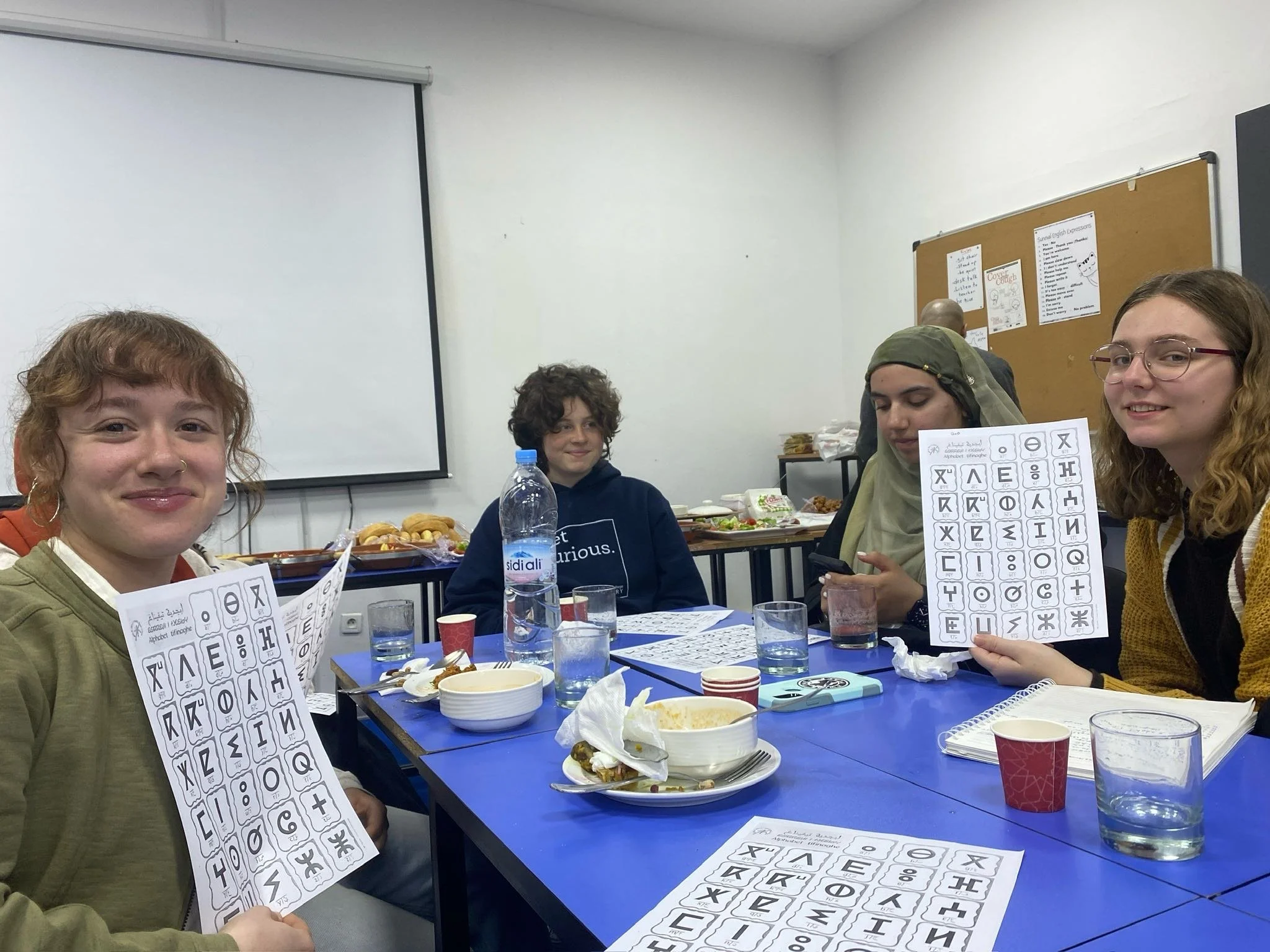 Students sit around a table holding up their worksheets