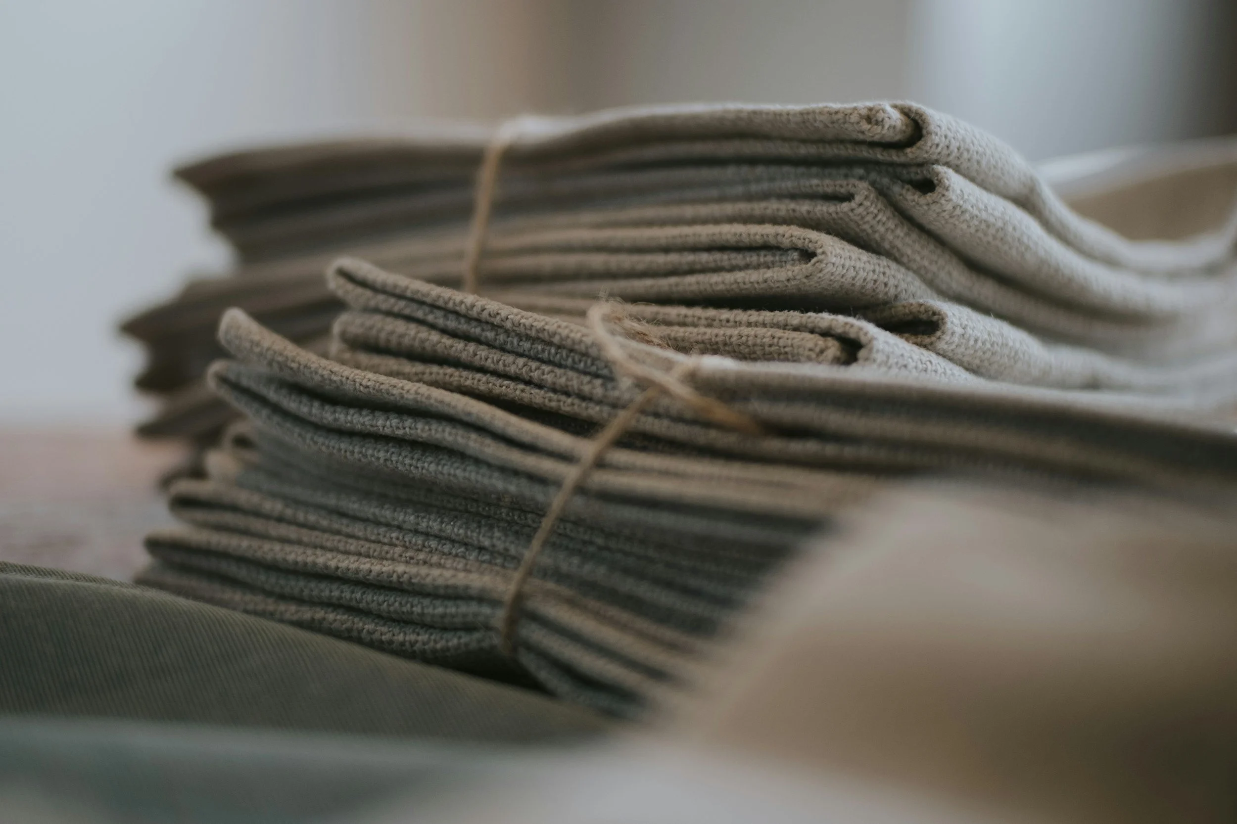 Stack of folded gray fabric napkins or cloths with a piece of string or cord tied around them.