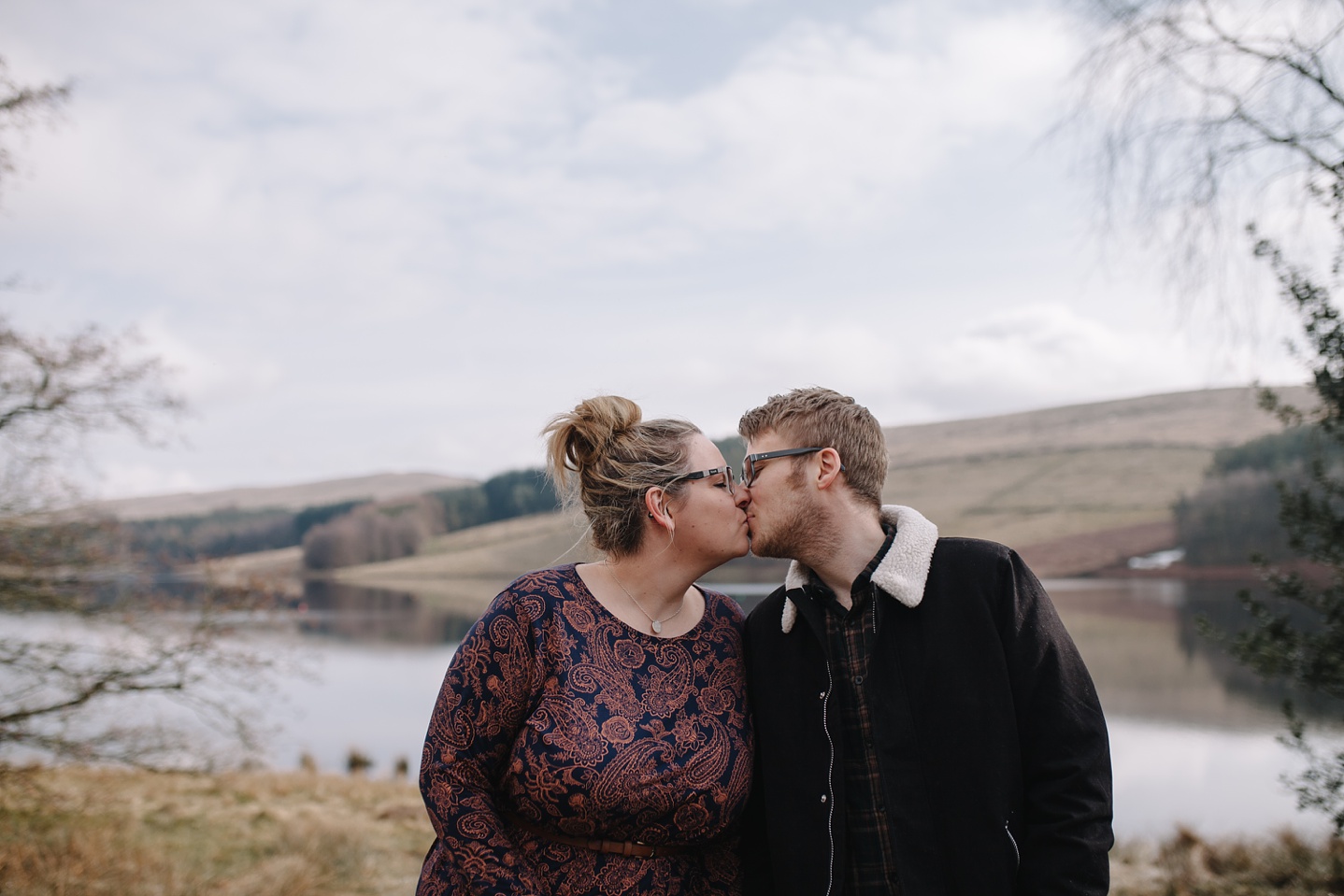 man and woman kissing in front of errwood reservoir 