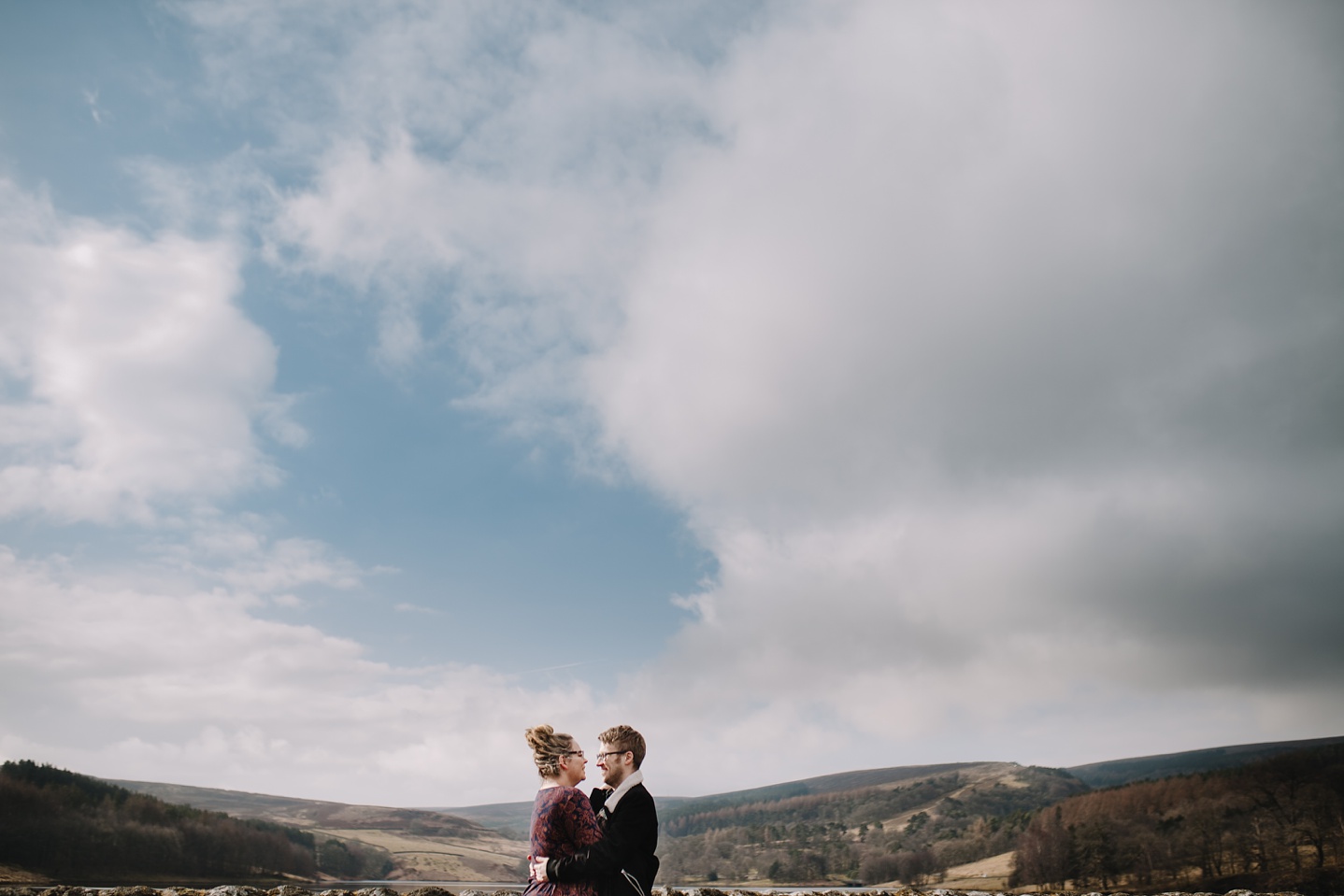 man and woman hugging with views of the Goyt Valley in the background