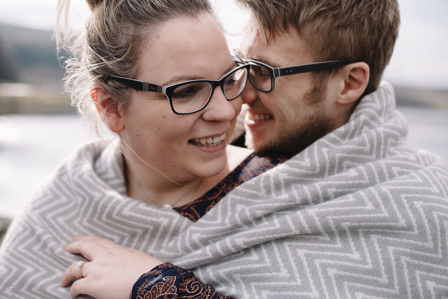 close up of man and woman wrapped in a blanket smiling and laughing