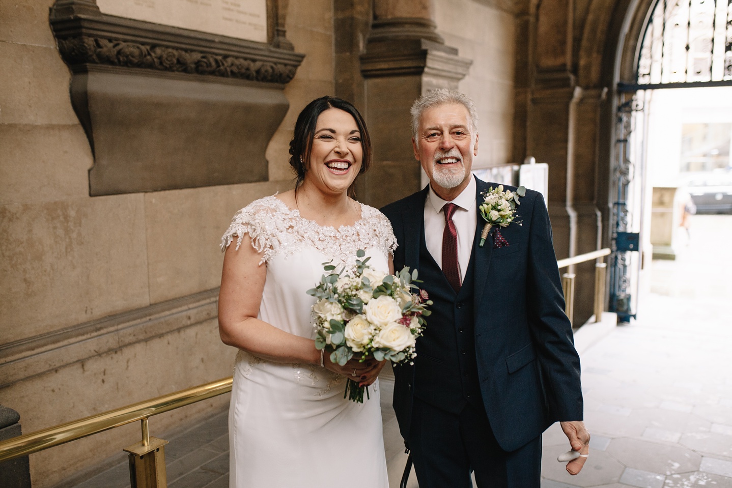 bride and father stood in the entrance of Sheffield Town Hall laughing