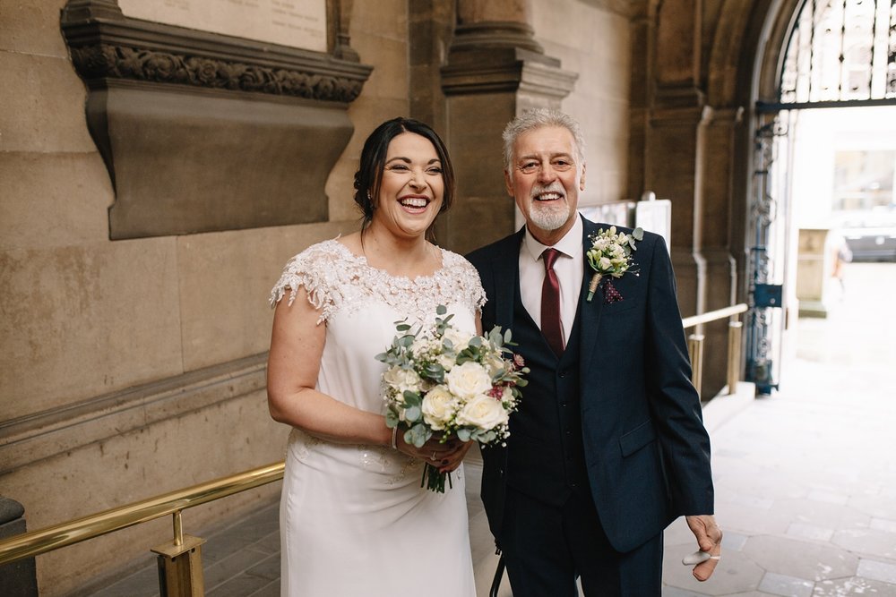 bride and father stood in the entrance of Sheffield Town Hall laughing