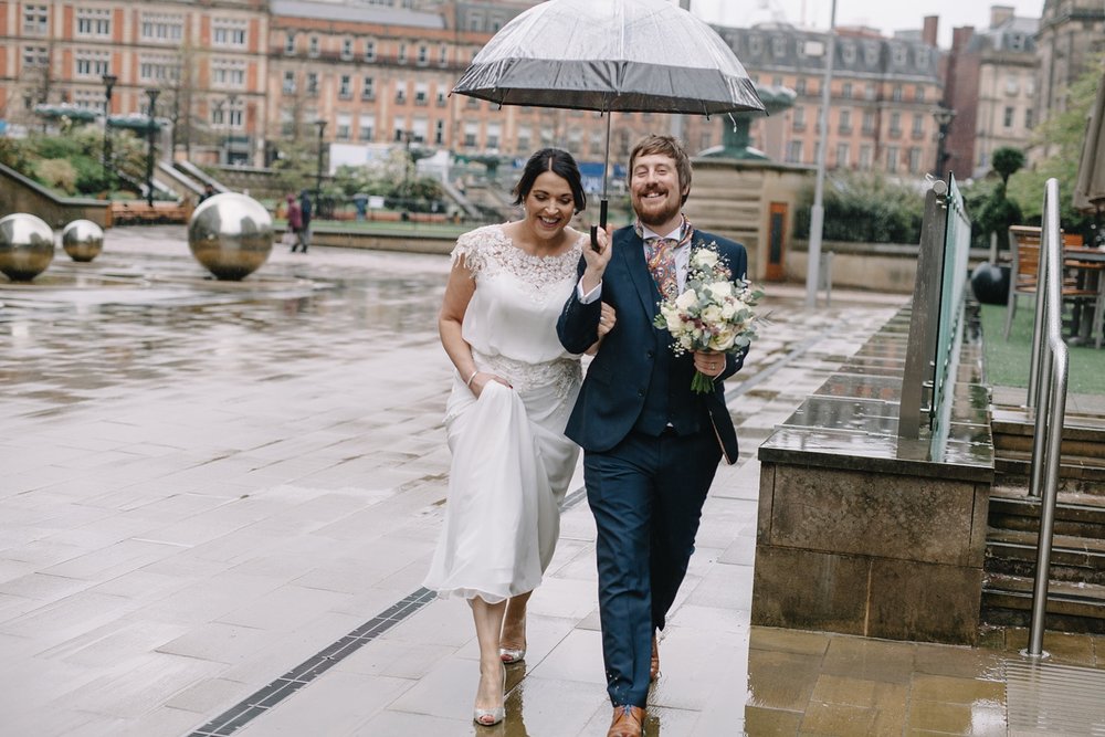 Bride and groom walking in the rain through Sheffield Peace Gardens