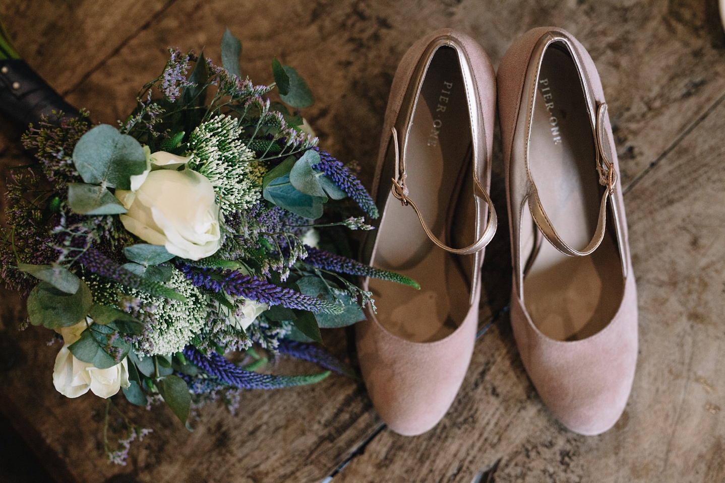 Bridal bouquet and wedding shoes on wooden table