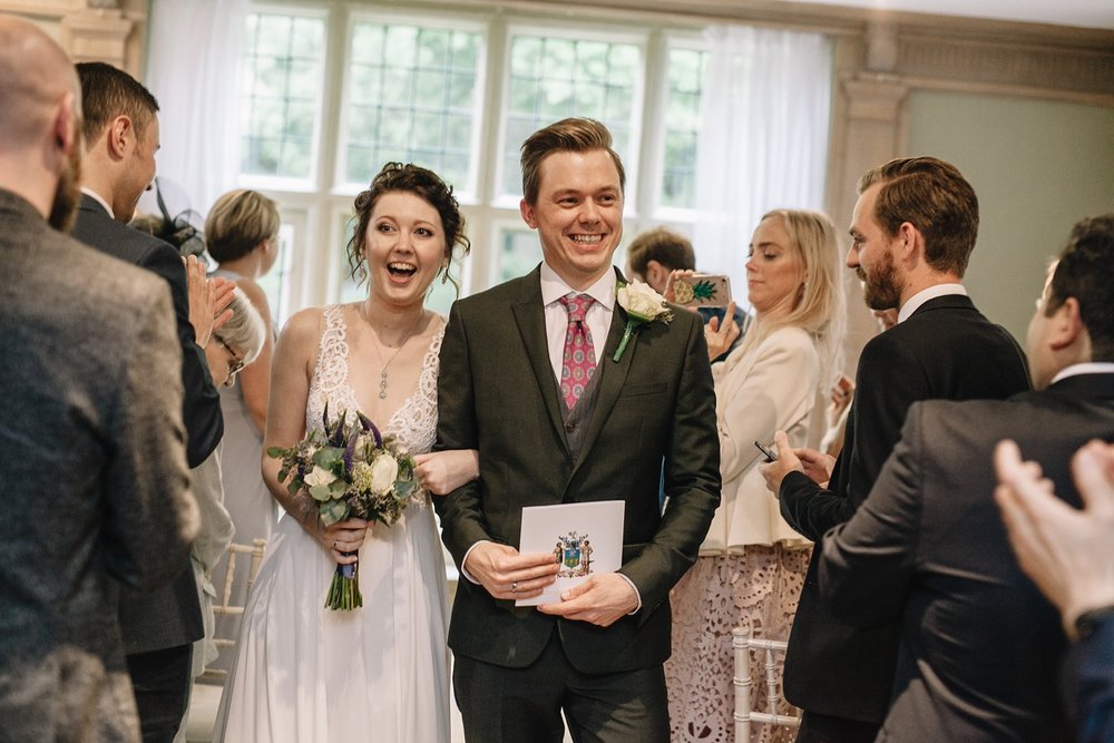 bride and groom laughing whilst walking down the aisle