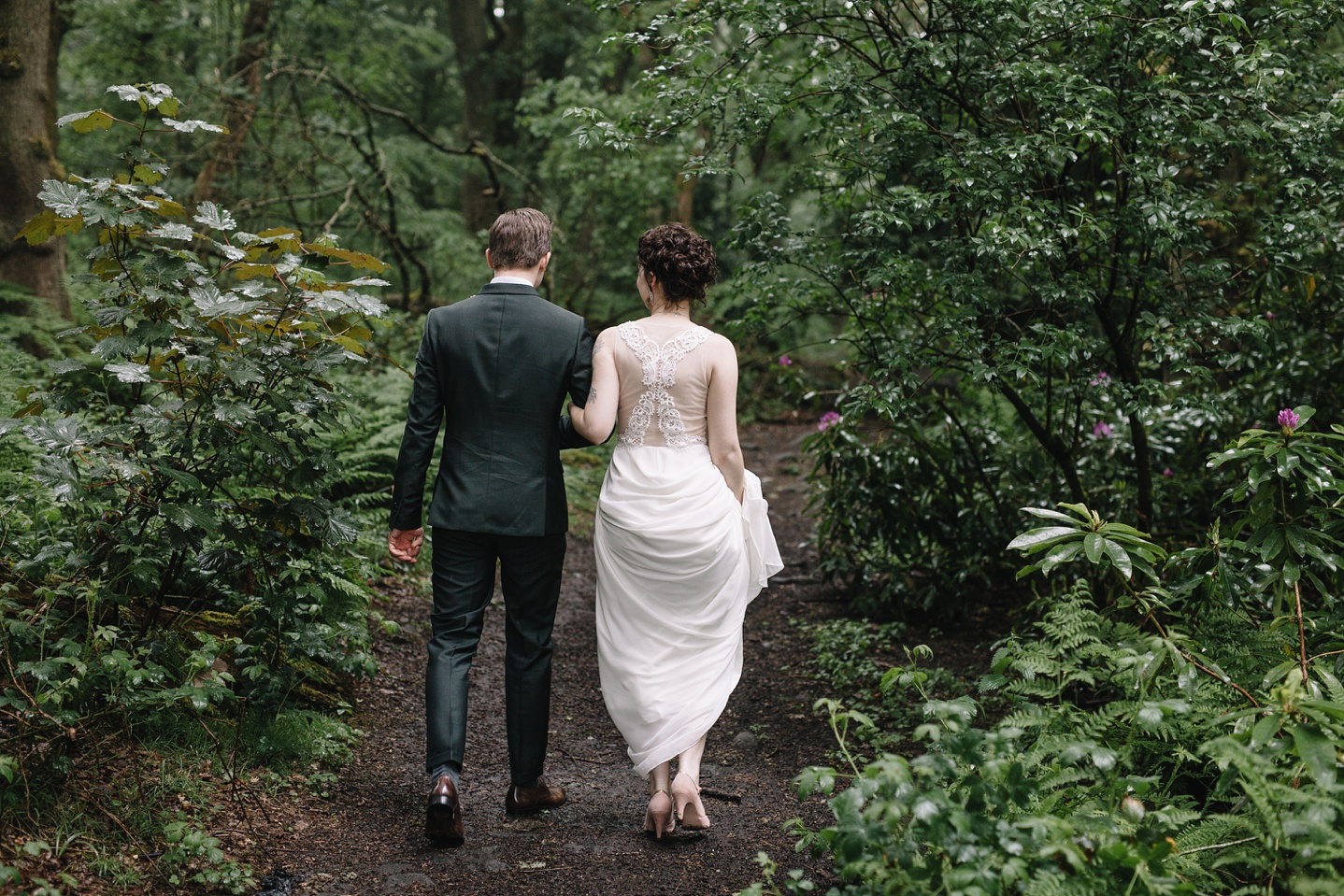 bride and groom walking through the woods at Whirlowbrook Hall