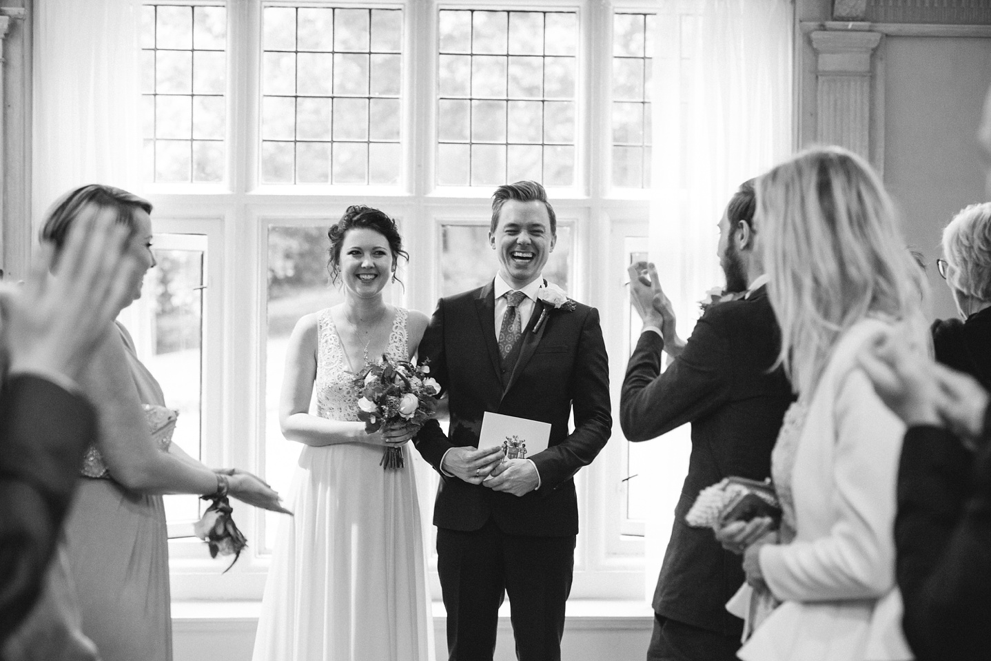 black and white photo of bride and groom holding their wedding certificate