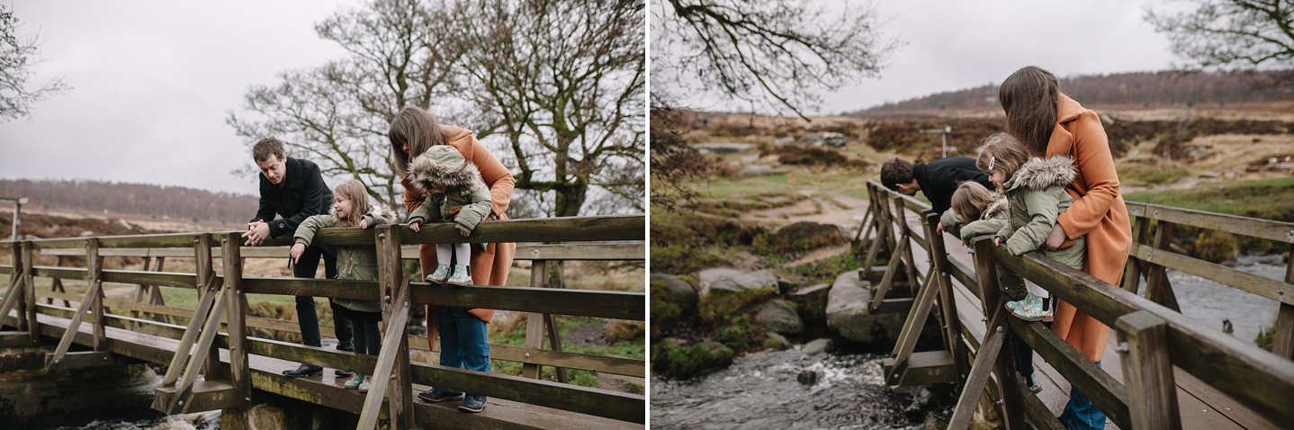 Mum and dad with two little girls stood on a bridge looking into a river