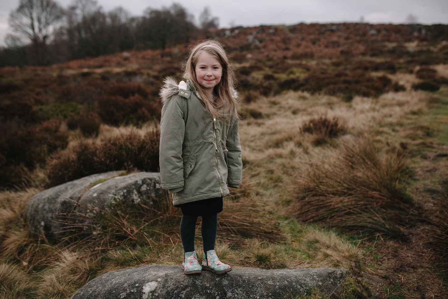 little girl stood on a rock smiling at the camera