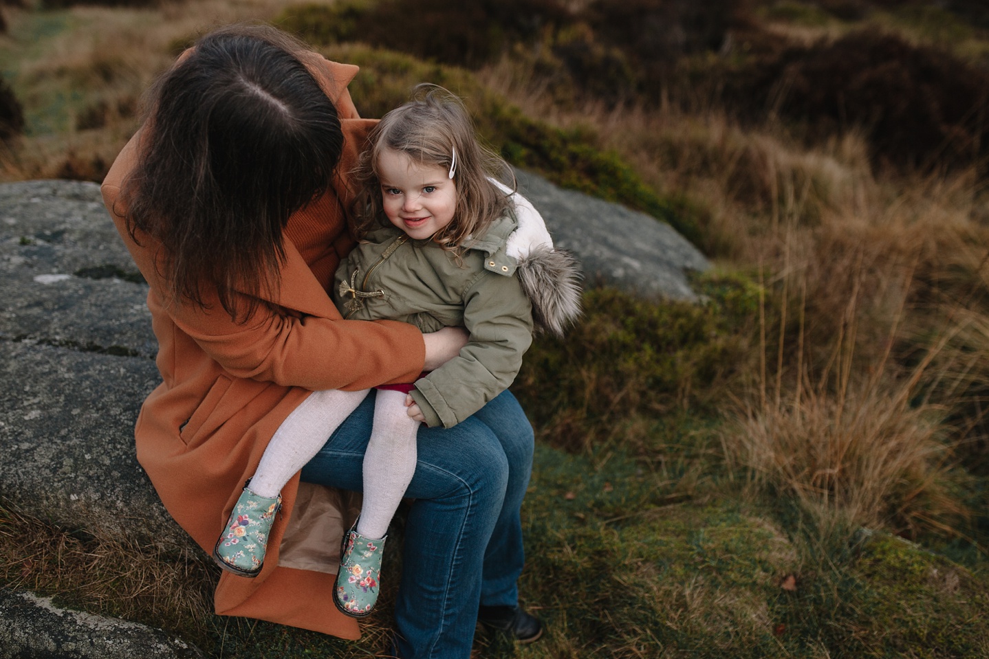 family photography of little girl sat on mums knee smiling at the camera in Sheffield