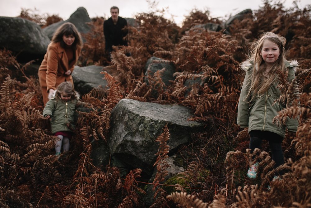 mum, dad and two little girls walking in amongst the brown ferns